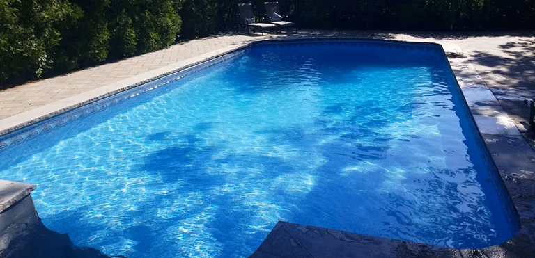 After renovation photo of a fully restored backyard swimming pool in Toronto. The new bright blue liner, clean water, and resurfaced edges highlight the professional pool transformation from old and damaged to modern and inviting. Expert pool renovation by local Toronto specialists.