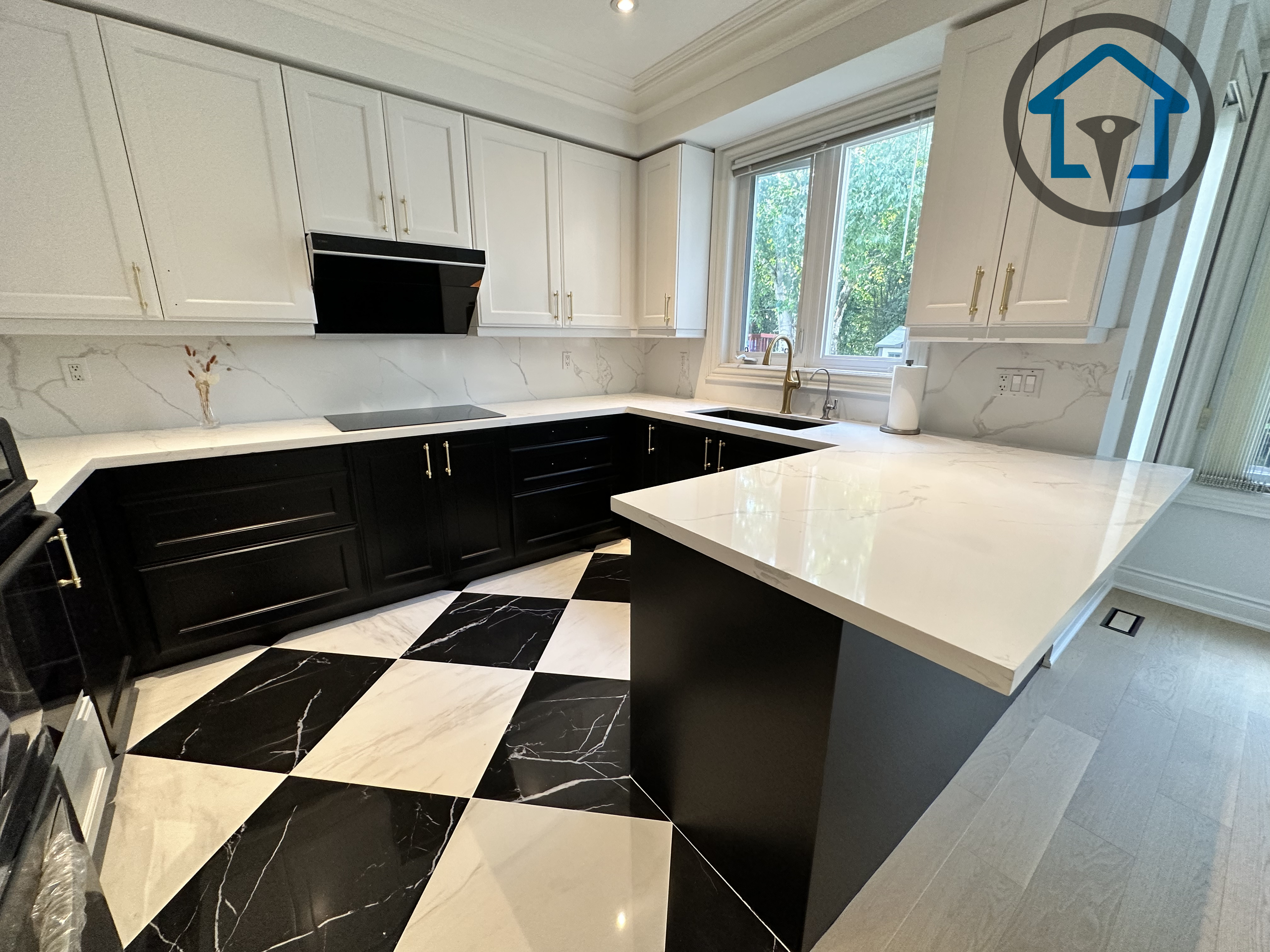 Modern kitchen completed as part of a North York interior renovation, featuring custom shaker-style cabinetry, a large quartz island, and bold black-and-white geometric tile flooring. Integrated lighting, clean millwork lines, and a functional layout create a refined yet practical cooking space, delivered by a professional Toronto renovation company specializing in full interior renovations.