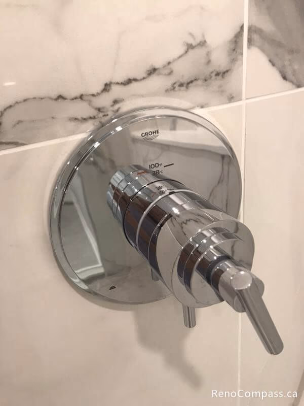 Professional installation of a Grohe chrome shower valve against luxury marble-veined wall tiles. A high-end finish for a modern master bathroom remodel in Markham.