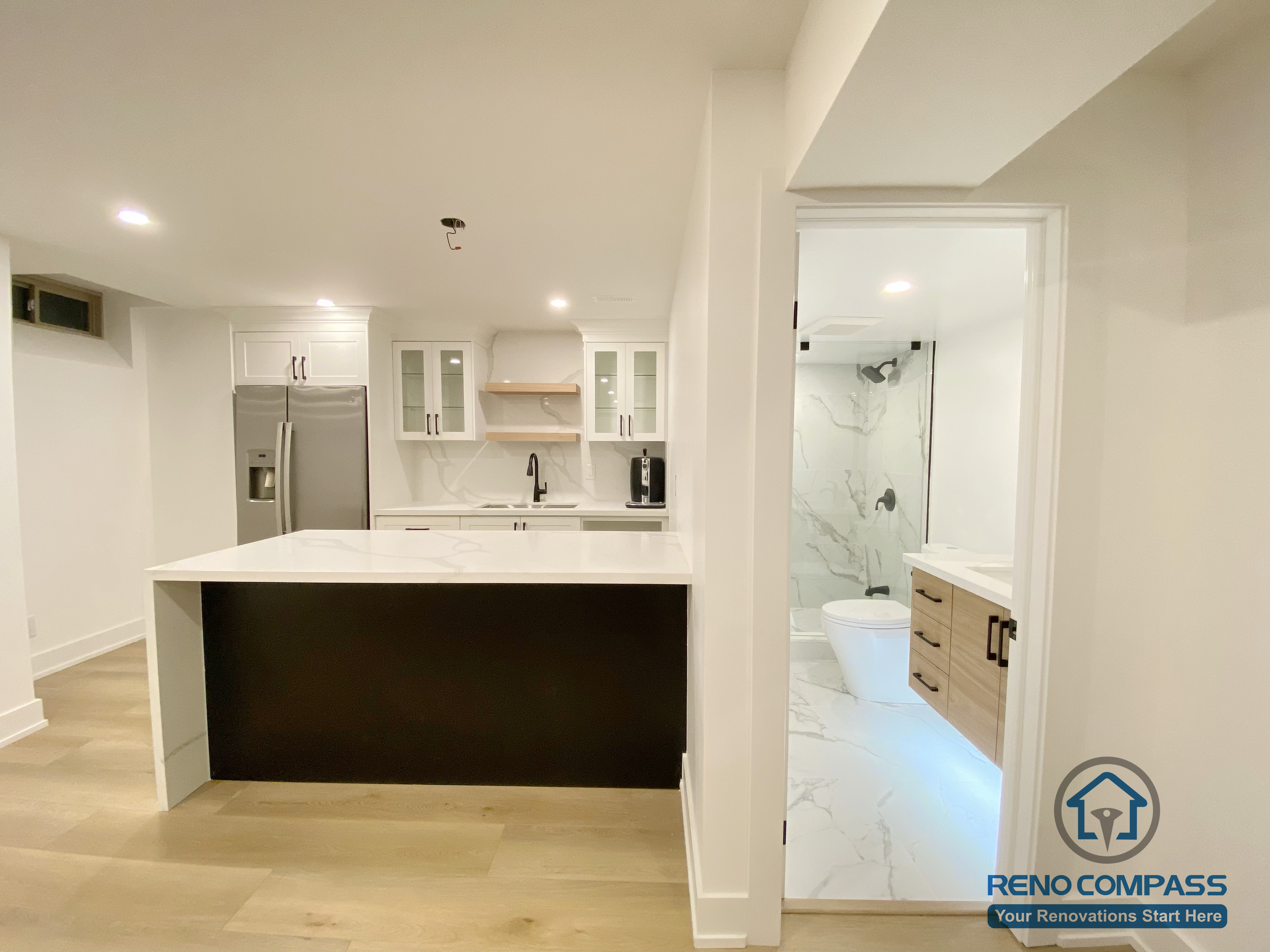 This modern basement kitchen includes a functional island layout, clean cabinetry, and efficient lighting. Designed to support entertaining and everyday use, the space seamlessly connects with the surrounding basement living areas.