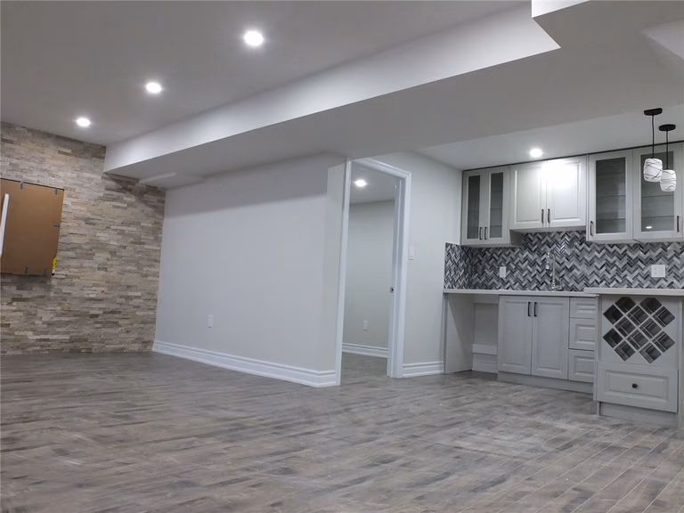 This Scarborough basement renovation project features a modern open-concept layout designed to maximize space, comfort, and functionality. The newly finished basement includes premium moisture-resistant flooring, recessed pot lights for bright and even illumination, and a spacious entertainment area perfect for family gatherings or rental potential. A custom-built bar and storage area enhance both convenience and style, creating a versatile living and leisure space. Completed by a professional Toronto basement renovation company, the project focuses on clean finishes, durable materials, and long-term property value improvement. Contractor: Reno Compass Inc.