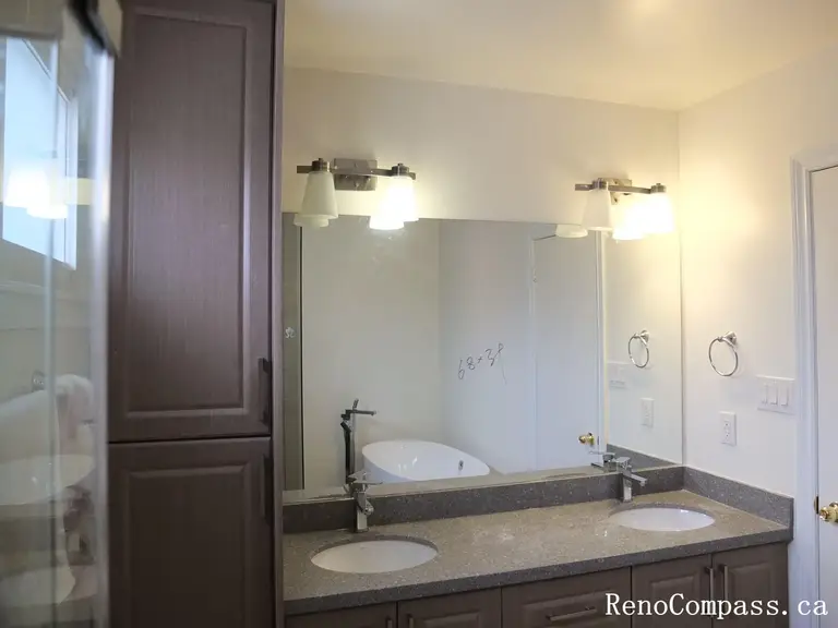 Bathroom renovation in North York featuring a double sink vanity, wall-mounted mirrors, quartz countertop, and integrated lighting. This Toronto interior renovation focuses on shared-use efficiency, balanced layout, and clean modern finishes suitable for family bathrooms.