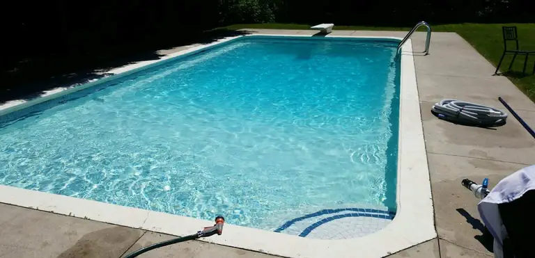 After renovation photo of a fully restored backyard swimming pool in Toronto. The new bright blue liner, clean water, and resurfaced edges highlight the professional pool transformation from old and damaged to modern and inviting. Expert pool renovation by local Toronto specialists.