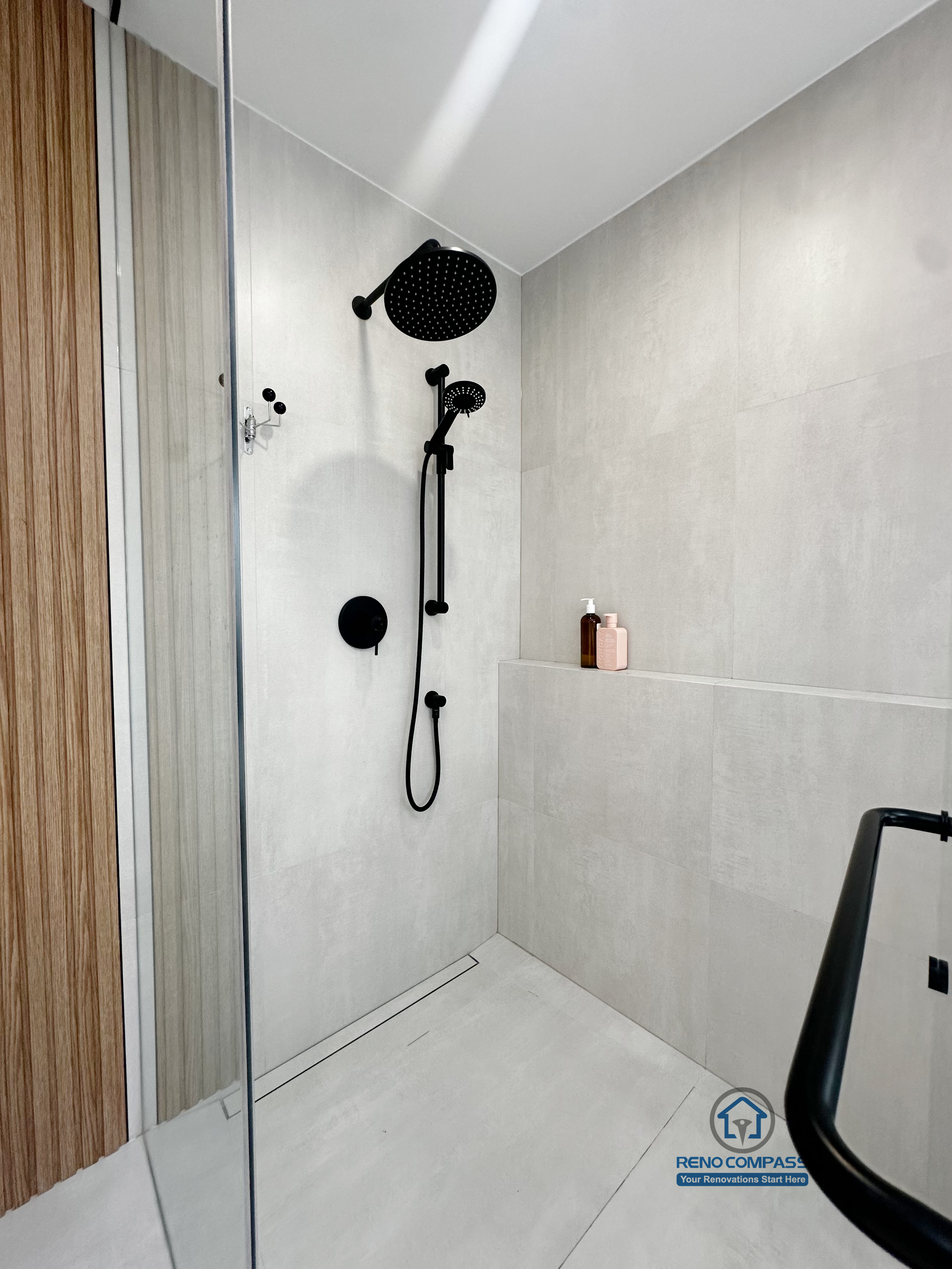 A curbless walk-in shower renovation in Markham, Toronto by Reno Compass, featuring matte black hardware, a built-in niche, and minimalist finishes designed for accessibility and everyday comfort.