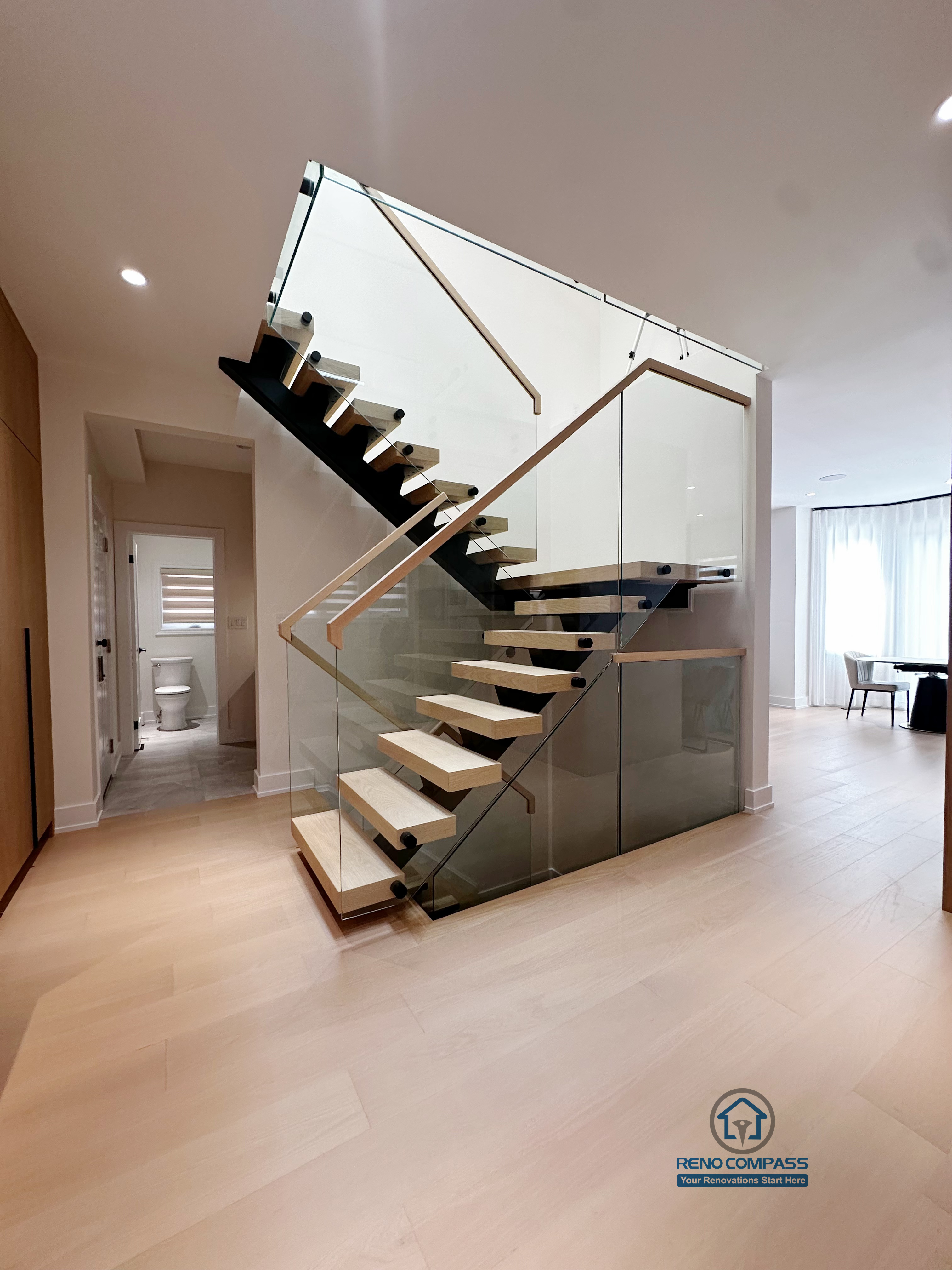 This overall view presents the full structure and proportions of the floating steel staircase. The clear steel framework defines the stair’s form, while solid wood treads and a tempered glass railing ensure safety without adding visual weight. Integrated into the main living area, the staircase becomes a key architectural element that connects levels and enhances openness throughout the space.