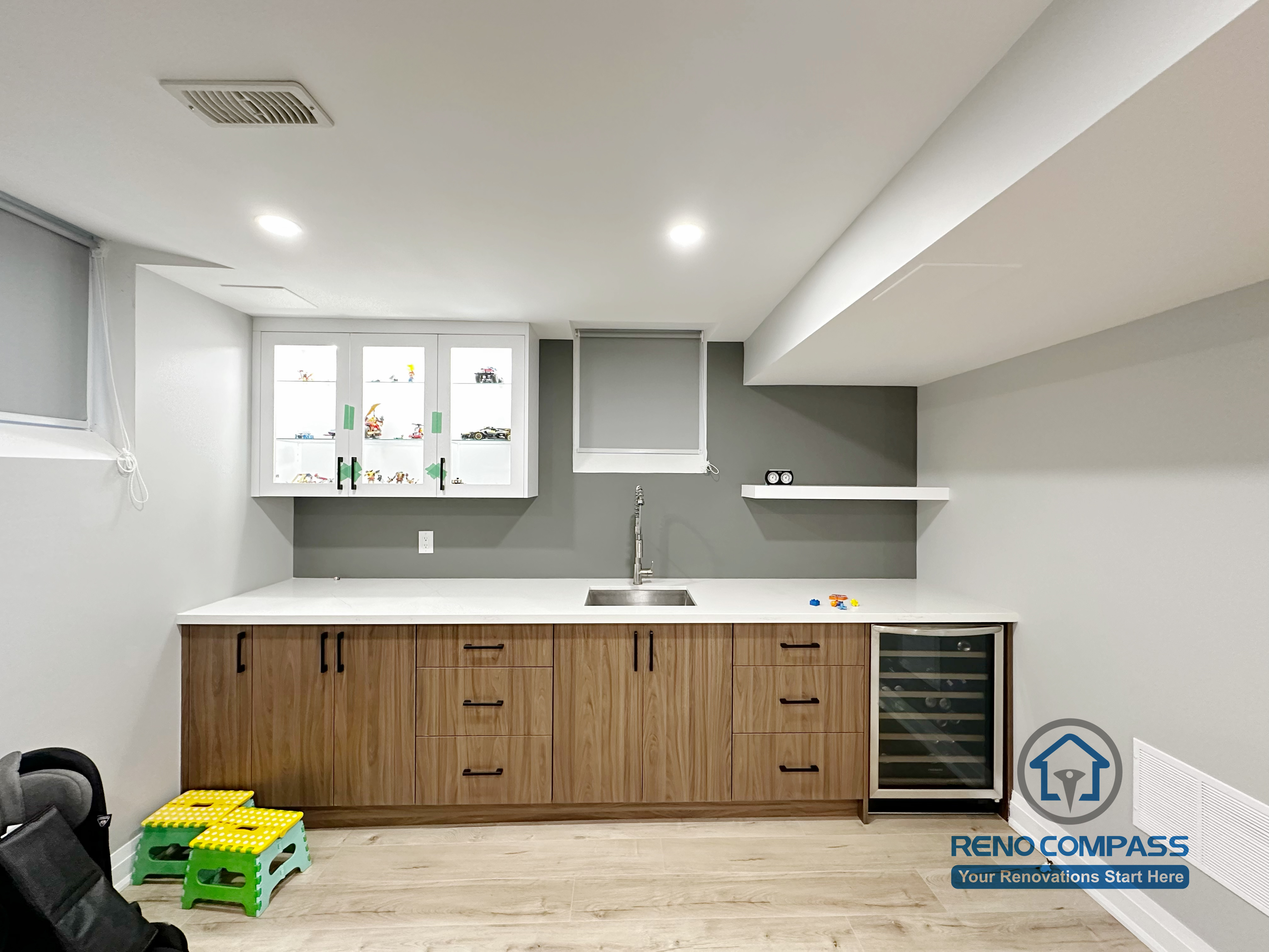 This Newmarket basement renovation features a custom wet bar with wood-tone cabinetry, quartz countertop, and an integrated beverage fridge. Designed for entertaining and family use, the finished basement bar area includes modern lighting, functional storage, and a clean contemporary layout that enhances the overall basement living space.
