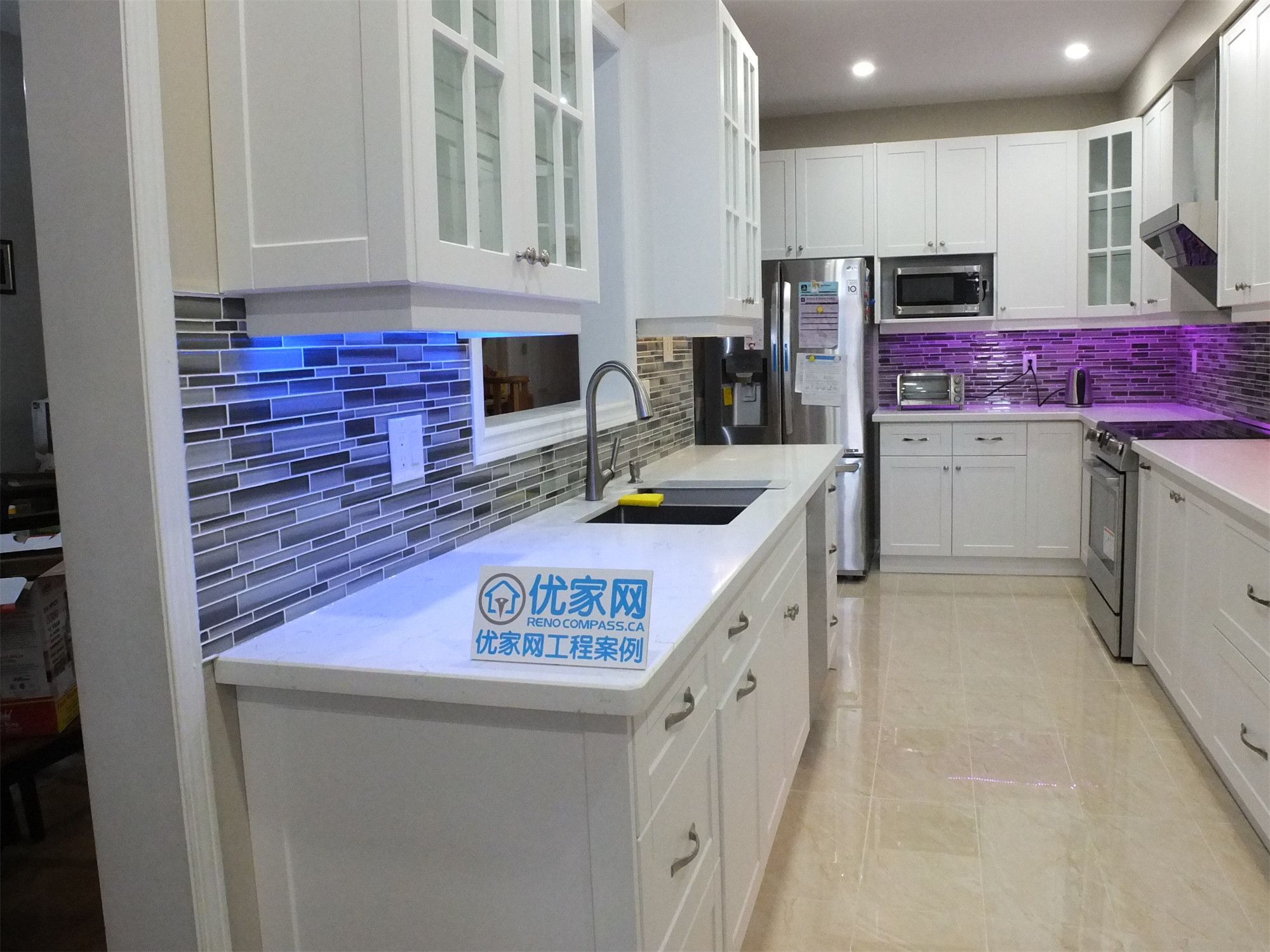 This Vaughan kitchen renovation highlights elegant white shaker cabinets with glass display doors, quartz countertops, and a modern glass mosaic backsplash enhanced by LED under-cabinet lighting. The clean layout and bright finishes create a stylish and functional cooking space. Completed by a trusted Toronto renovation company, the design blends modern aesthetics with everyday practicality.