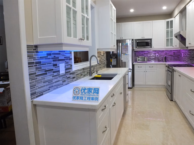 This Vaughan kitchen renovation highlights elegant white shaker cabinets with glass display doors, quartz countertops, and a modern glass mosaic backsplash enhanced by LED under-cabinet lighting. The clean layout and bright finishes create a stylish and functional cooking space. Completed by a trusted Toronto renovation company, the design blends modern aesthetics with everyday practicality.