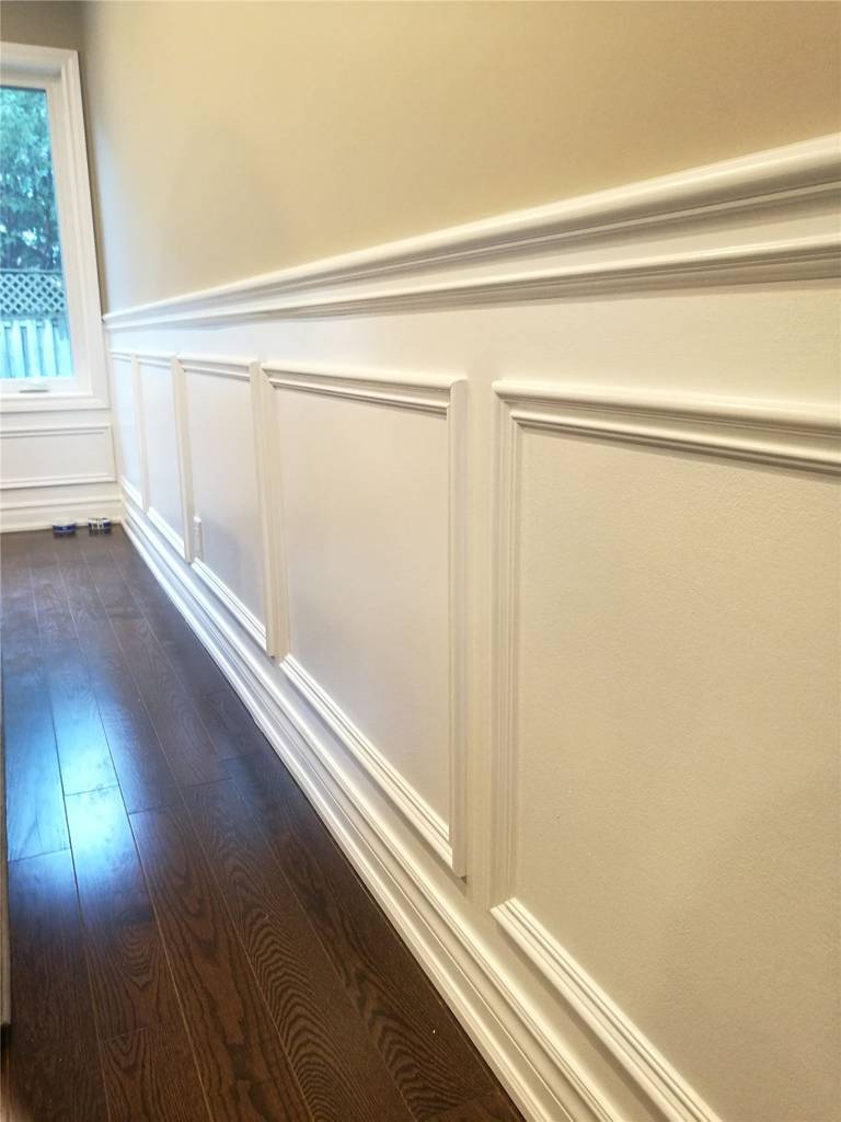 This Newmarket interior renovation features custom wall paneling and wainscoting with clean trim lines and precise detailing. Paired with dark hardwood flooring, the refined wall finish adds depth and elegance to the space, highlighting the craftsmanship and finish quality delivered by a professional Toronto renovation company.