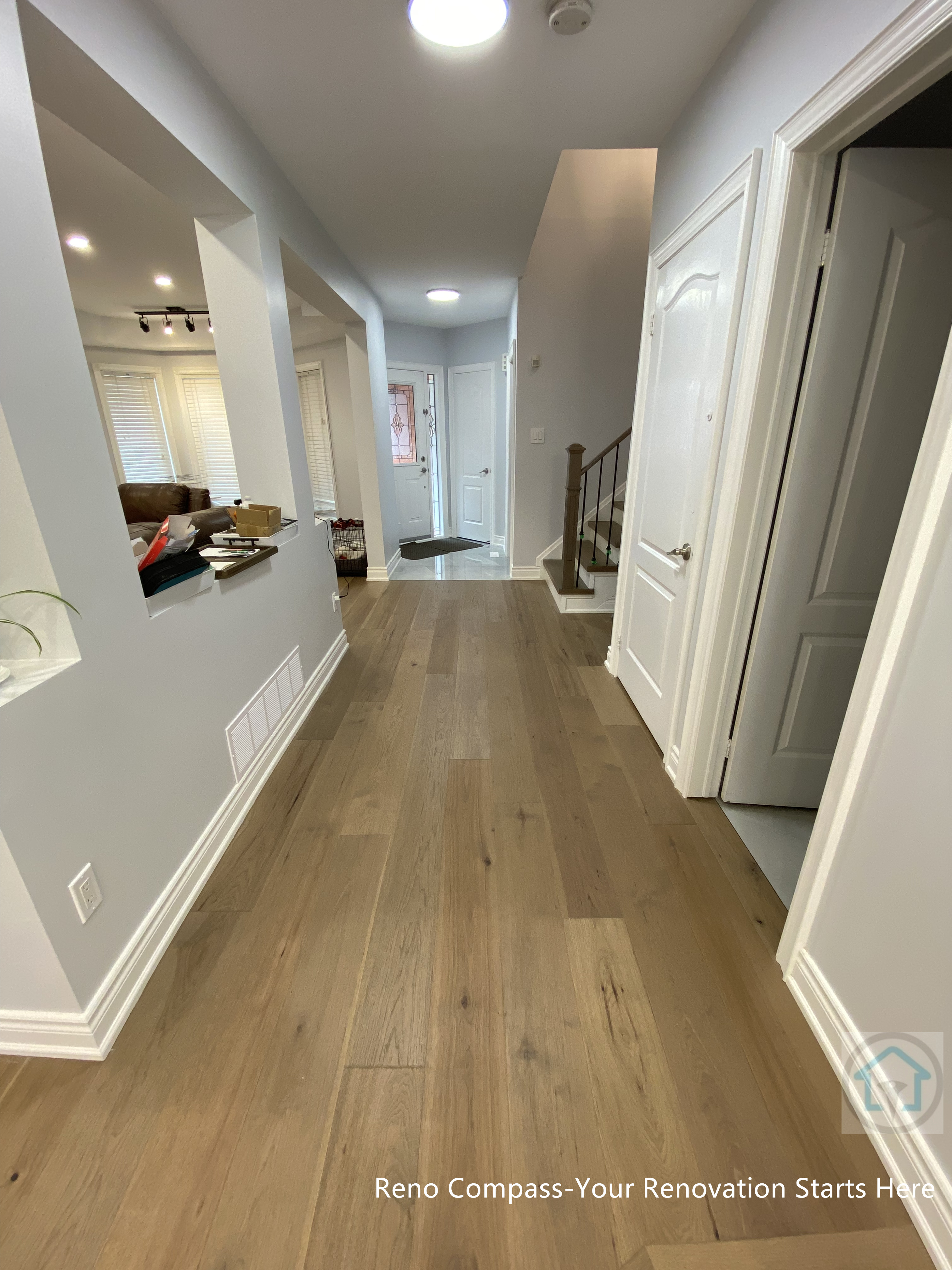 This Newmarket interior renovation features a bright and well-organized main floor hallway with wide-plank hardwood flooring and neutral wall tones. The open sightline enhances natural flow between living areas, while recessed lighting and clean trim details create a modern, cohesive transition space that improves everyday circulation and overall functionality.