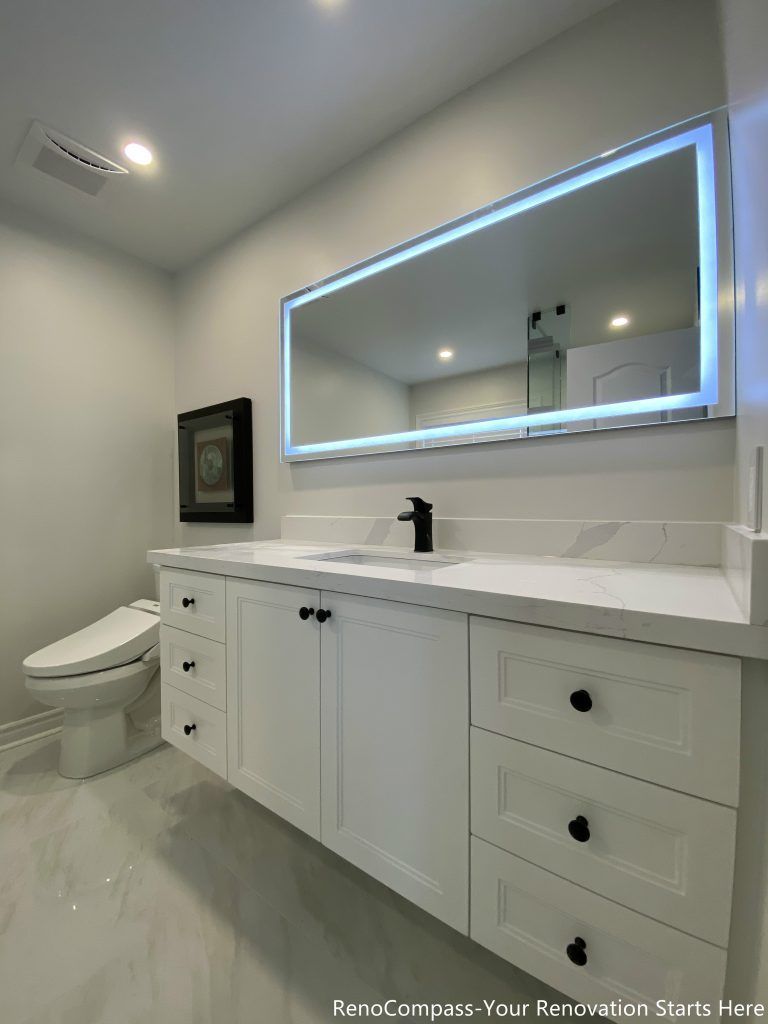 This Markham bathroom renovation shows the vanity from a side angle, highlighting the full-length countertop, classic white cabinetry, and integrated LED mirror. The extended layout enhances storage capacity and improves circulation, while soft lighting and neutral finishes keep the bathroom feeling open, bright, and easy to use on a daily basis.
City: Markham · Toronto contractor: Reno Compass