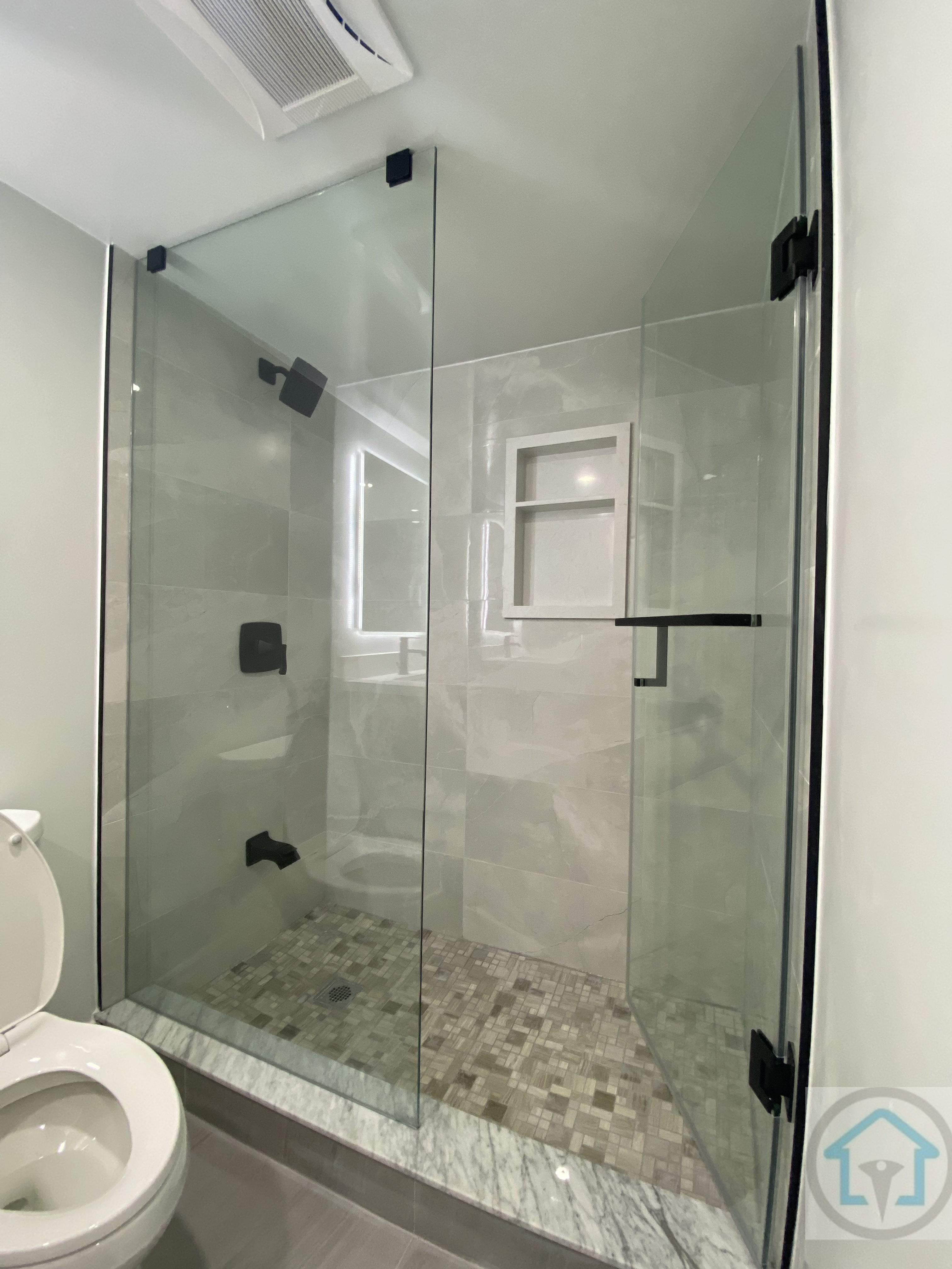 This Aurora basement bathroom renovation features a sleek modern glass shower with marble-style tiles, a contemporary toilet, and bright recessed lighting. The clean design maximizes space and creates a functional and elegant basement bathroom. Contractor: Reno Compass Inc., City: Aurora.