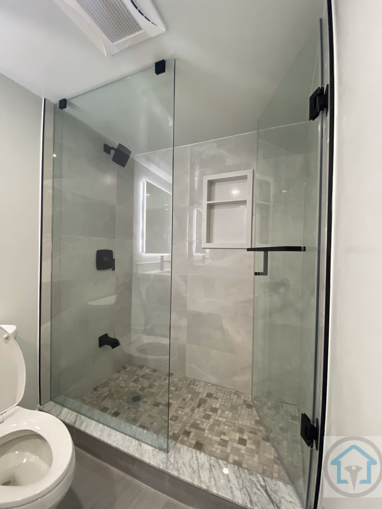 This Aurora basement bathroom renovation features a sleek modern glass shower with marble-style tiles, a contemporary toilet, and bright recessed lighting. The clean design maximizes space and creates a functional and elegant basement bathroom. Contractor: Reno Compass Inc., City: Aurora.