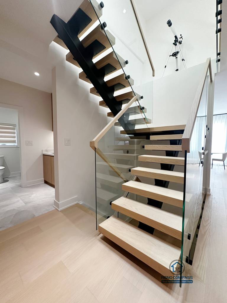 This detail view highlights the craftsmanship of the floating steel staircase, featuring solid wood treads paired with a tempered glass railing system. The design emphasizes clean lines, structural clarity, and safety, while maintaining visual openness and a seamless connection between levels.