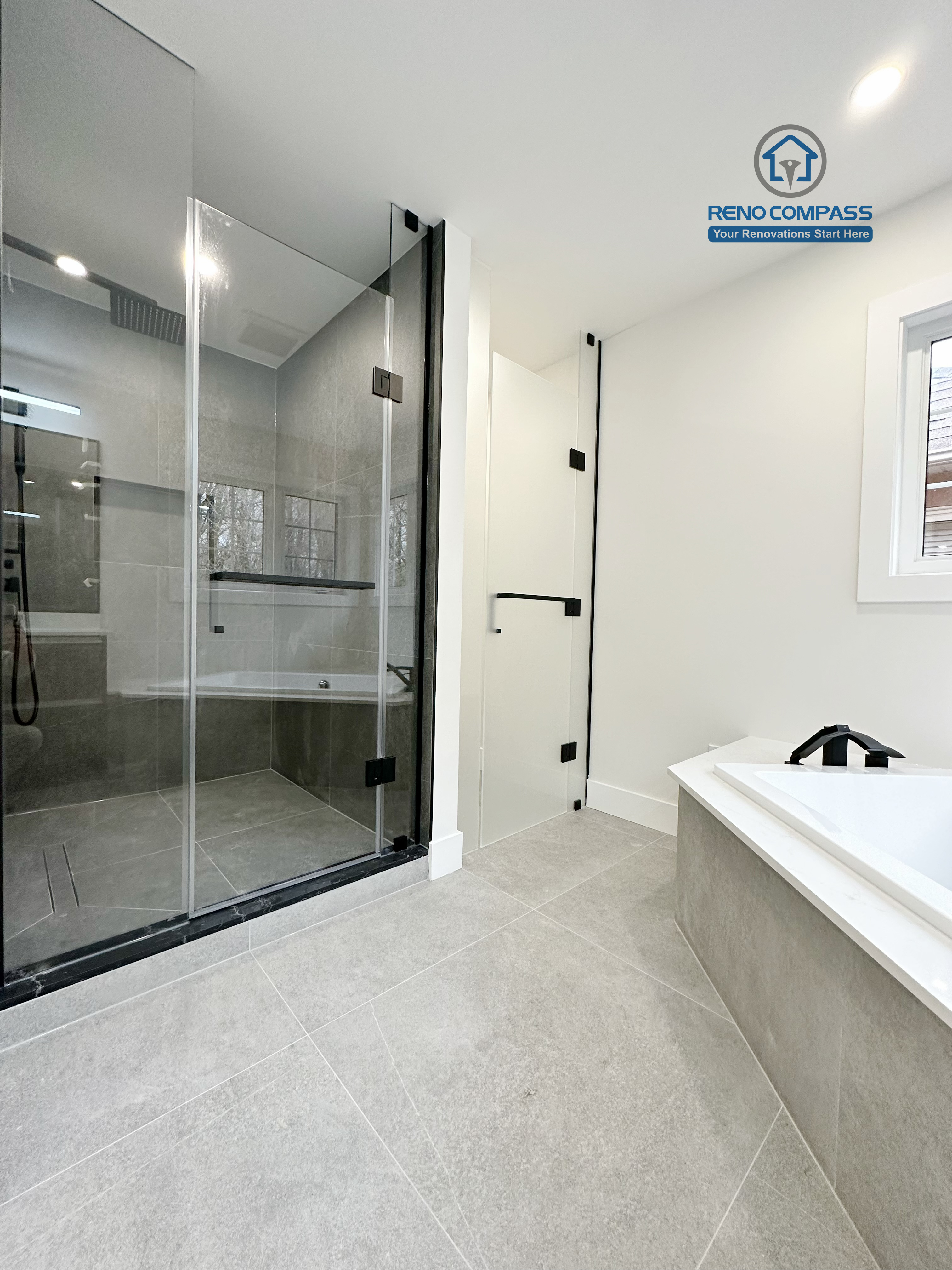 Modern bathroom renovation in Richmond Hill featuring a frameless glass shower with dark tile finishes alongside a built-in soaking tub, creating a balanced layout that combines functionality, comfort, and contemporary design.