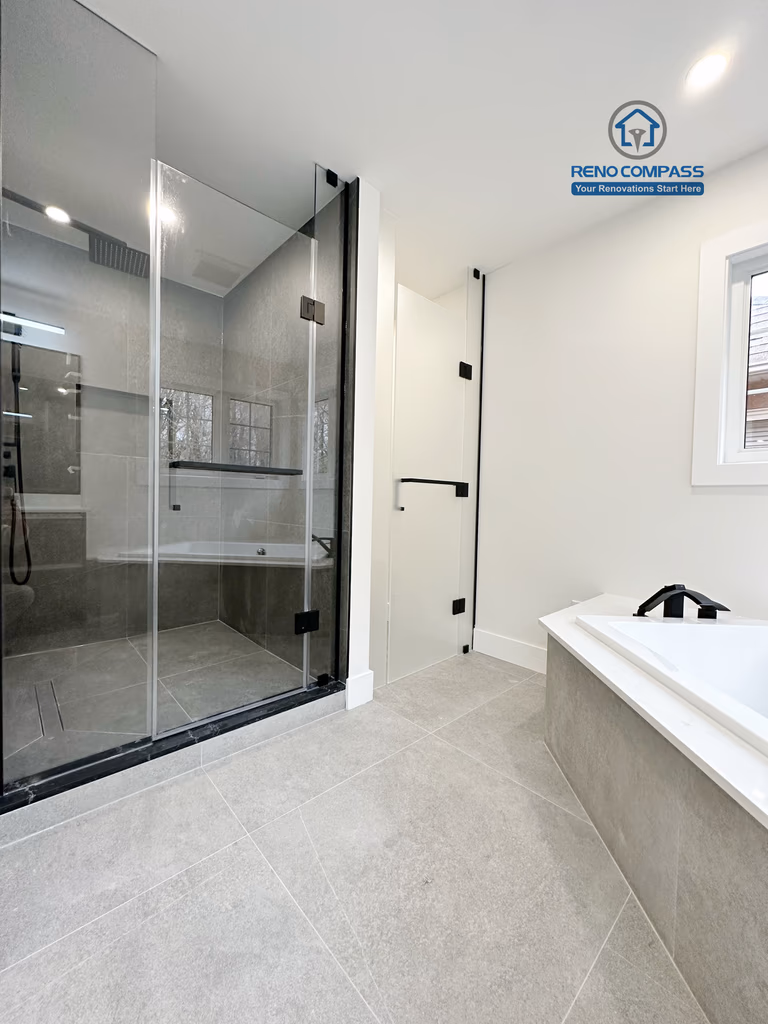 Modern bathroom renovation in Richmond Hill featuring a frameless glass shower with dark tile finishes alongside a built-in soaking tub, creating a balanced layout that combines functionality, comfort, and contemporary design.