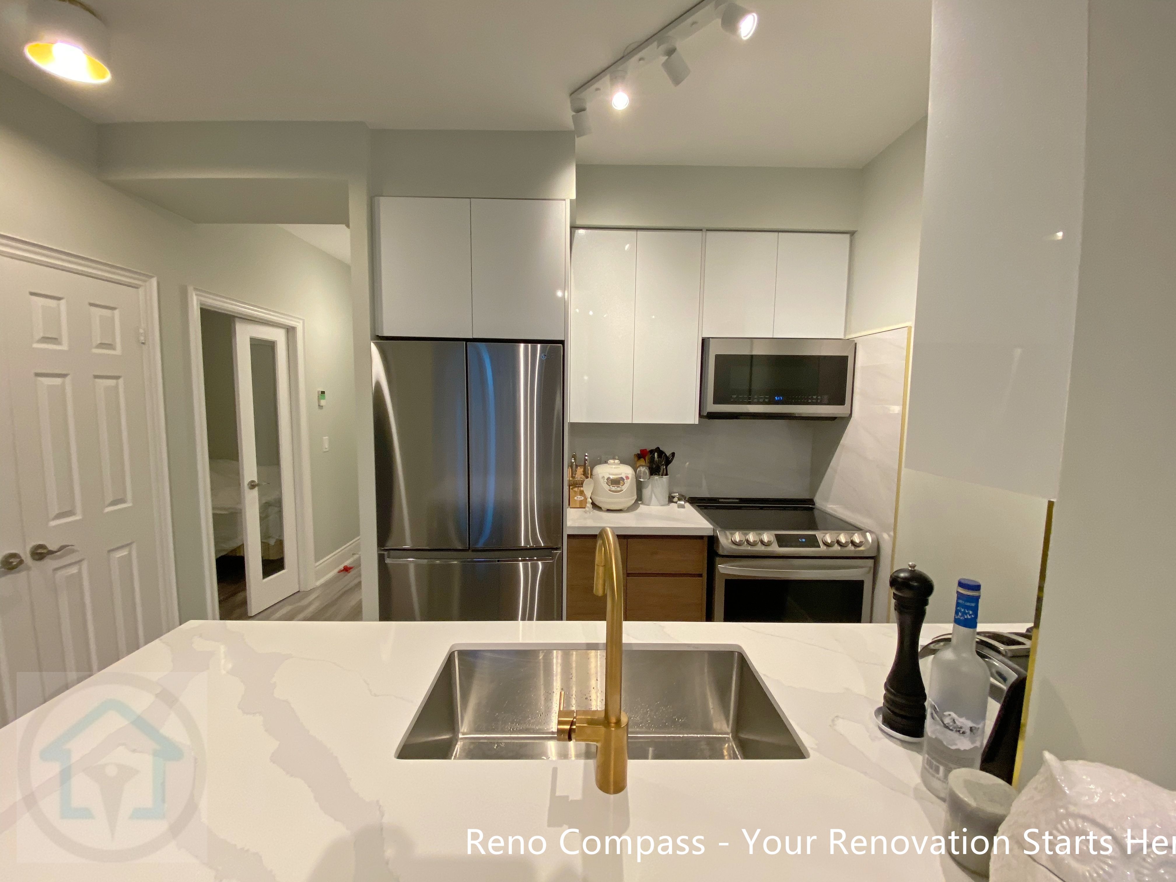 This North York condo kitchen renovation highlights a clean, functional layout with a quartz countertop island, undermount sink, and brushed brass faucet as a subtle focal point. Glossy white cabinetry, stainless steel appliances, and track lighting enhance brightness while maximizing space efficiency. The updated design improves workflow, storage, and daily usability, making the kitchen well-suited for modern condo living and long-term property value.