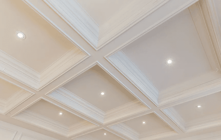 This Richmond Hill interior renovation highlights a refined living space with a coffered ceiling, custom wainscoting, and detailed hardwood flooring with inlay borders. Large windows with plantation shutters enhance natural light, while classic millwork and clean architectural lines create a timeless, elegant interior renovation result.