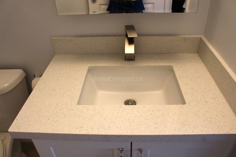 A modern bathroom vanity featuring a sleek rectangular sink, quartz countertop, and contemporary brushed nickel faucet. This elegant Mississauga home renovation by RenoCompass highlights fine craftsmanship and timeless design.