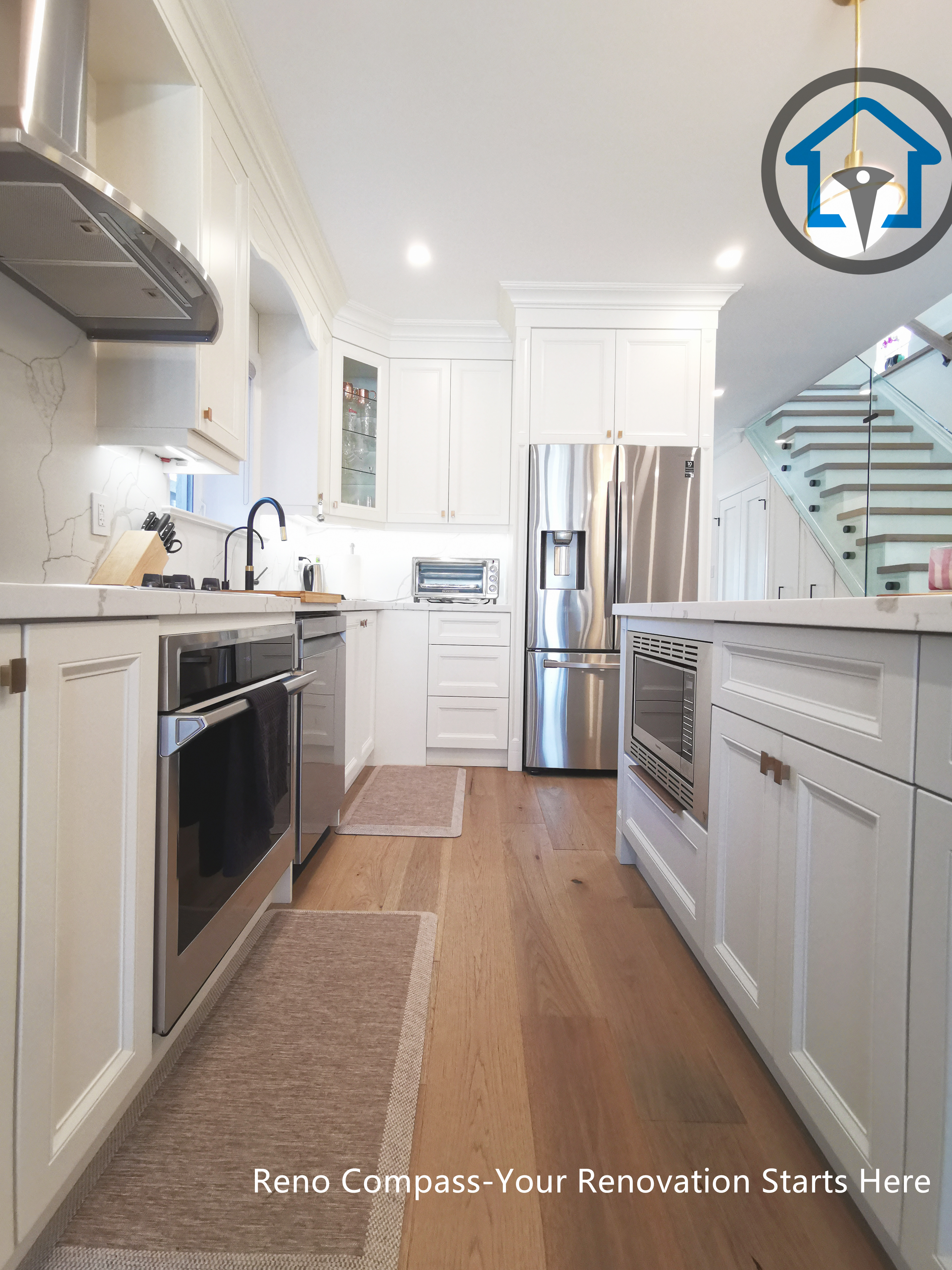 This image showcases a galley-style kitchen from a North York interior renovation, designed to maximize efficiency, storage, and clear circulation. Custom white cabinetry lines both sides of the space, paired with quartz countertops, stainless steel appliances, and integrated lighting for a clean and functional layout. Warm hardwood flooring softens the crisp finishes, while the extended sightline toward the staircase reinforces the open, connected interior design. Completed by a Toronto renovation company, this kitchen renovation highlights practical planning, balanced proportions, and long-term usability for North York homes.