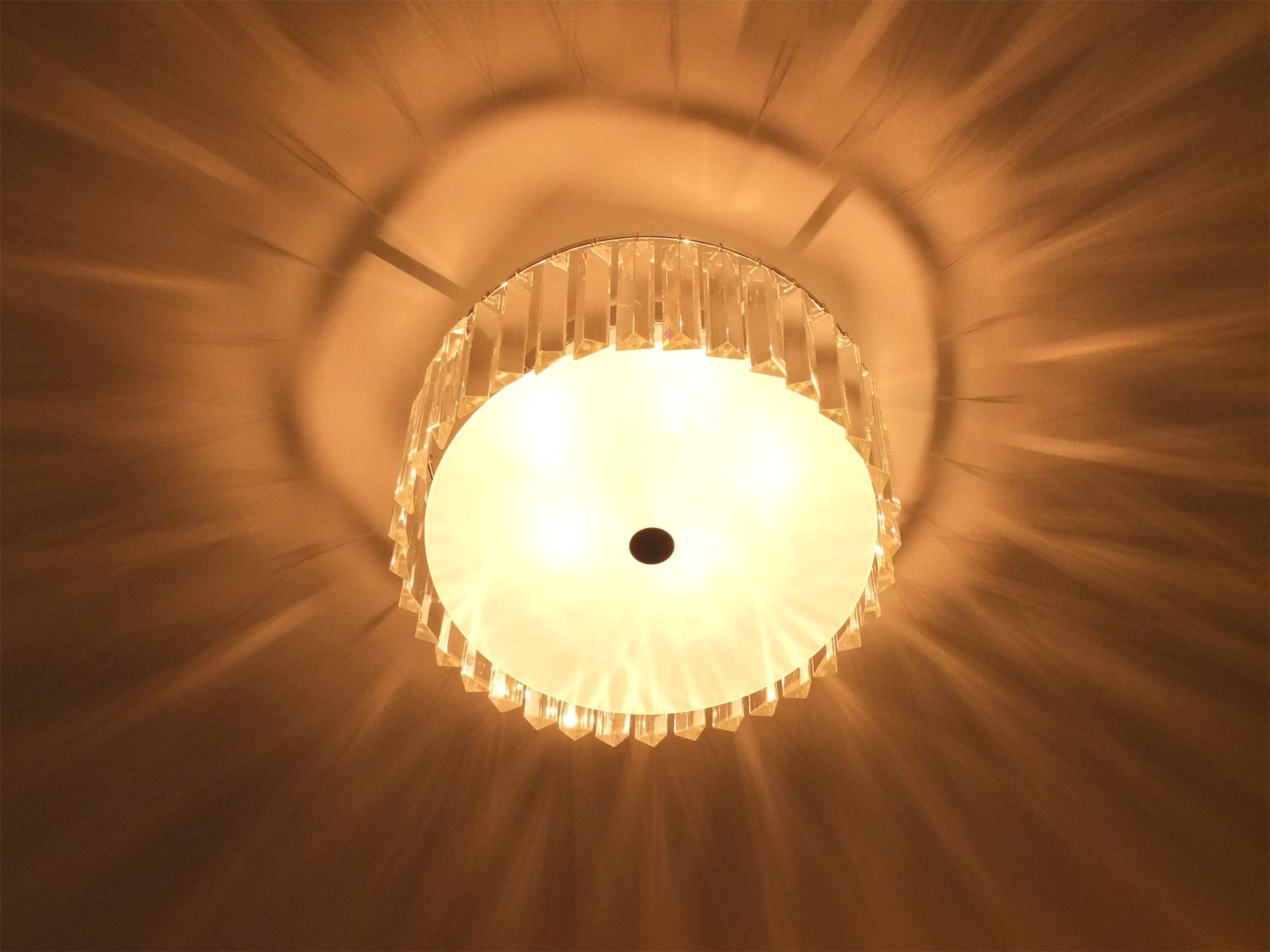 This Kleinburg interior renovation highlights a modern crystal ceiling light fixture that adds warmth and elegance to the room. The layered glass elements create beautiful light reflections across the ceiling, enhancing the overall ambiance. This decorative lighting detail complements the clean, contemporary interior design and contributes to the refined atmosphere of the renovated home.