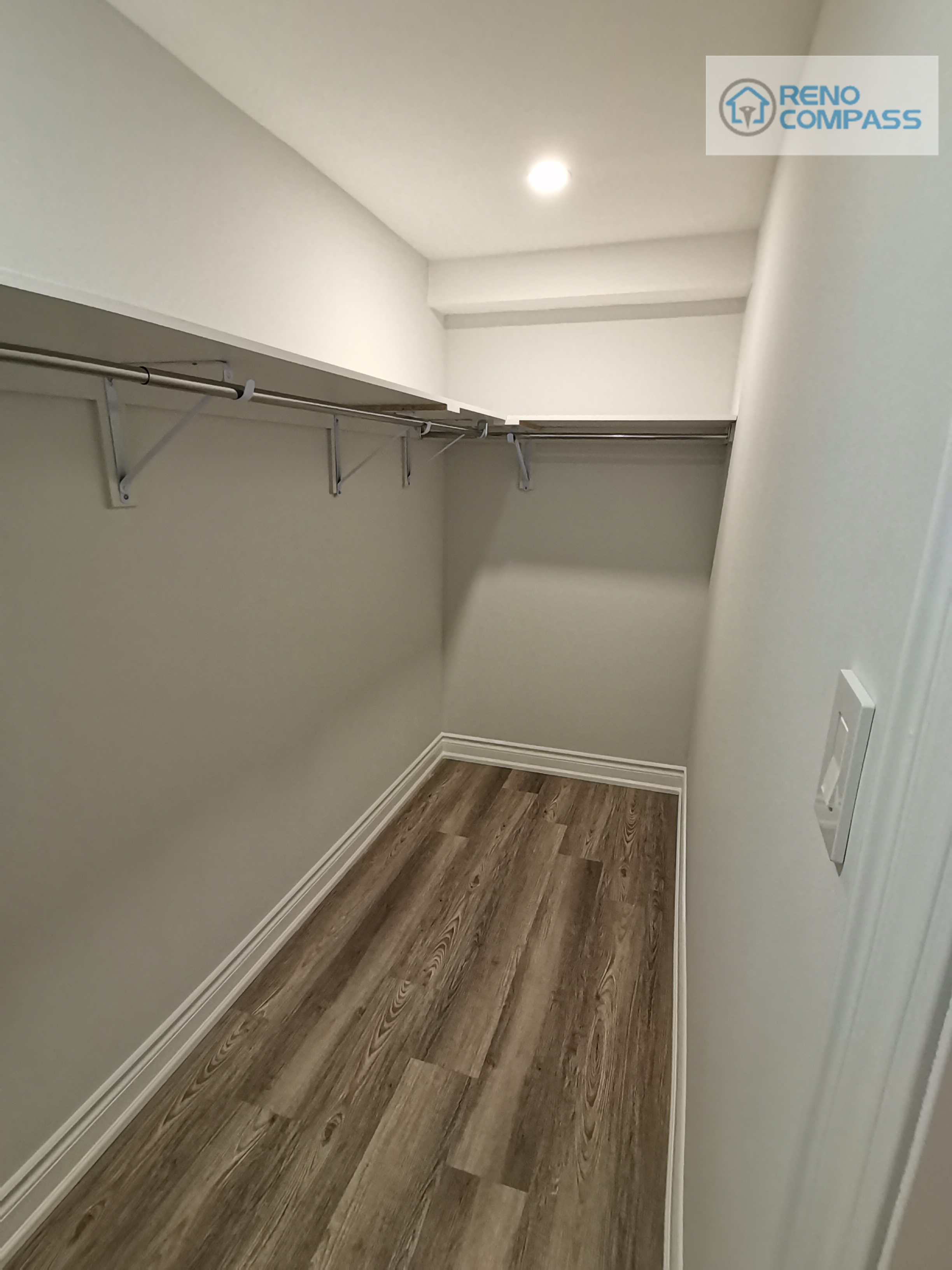This walk-in closet was integrated into the Woodbridge basement renovation to provide functional storage without compromising floor space. Open hanging rods and wall-mounted shelving create flexible organization for seasonal clothing, storage bins, or utility use. Durable wood-look flooring and recessed ceiling lighting keep the space bright and practical, making it a valuable extension of the finished basement layout.
