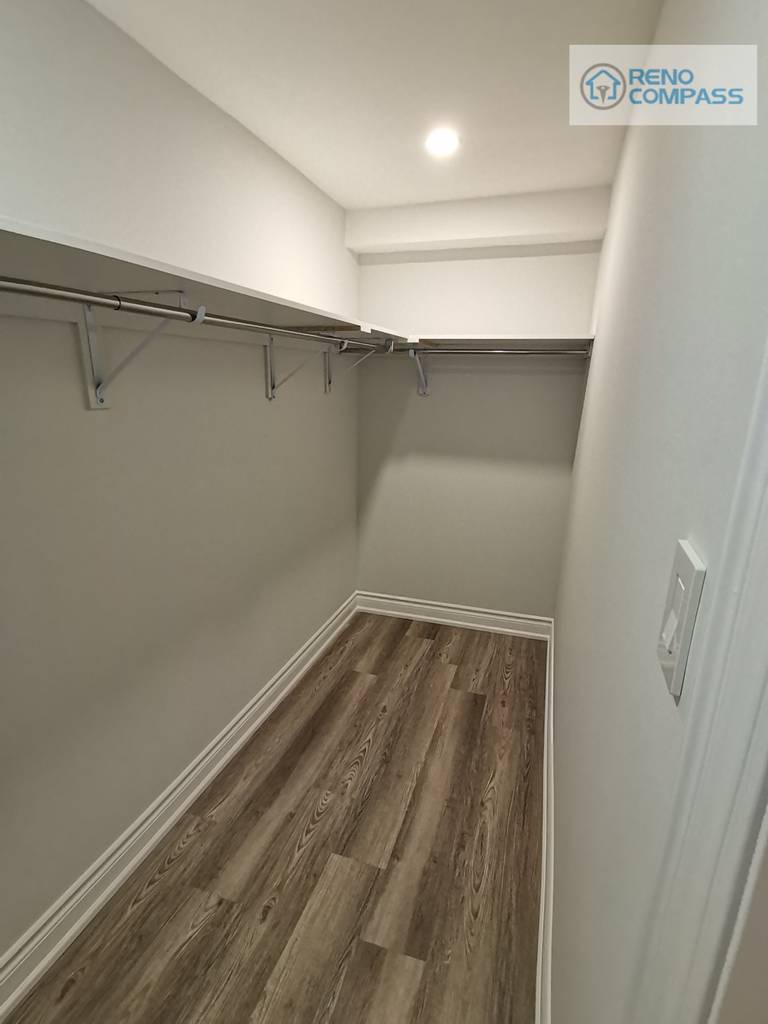 This walk-in closet was integrated into the Woodbridge basement renovation to provide functional storage without compromising floor space. Open hanging rods and wall-mounted shelving create flexible organization for seasonal clothing, storage bins, or utility use. Durable wood-look flooring and recessed ceiling lighting keep the space bright and practical, making it a valuable extension of the finished basement layout.