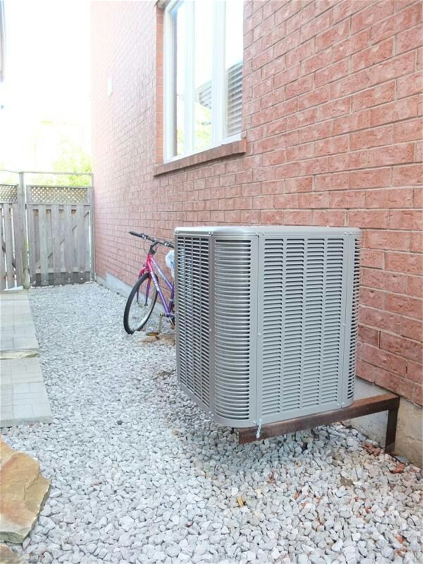Professional outdoor air conditioner condenser installation by Reno Compass in Toronto. This energy-efficient HVAC unit is securely mounted on a raised stand with proper drainage and ventilation clearance, ensuring optimal cooling performance, durability, and safe operation for residential homes. Installed by licensed technicians for long-term reliability and comfort.