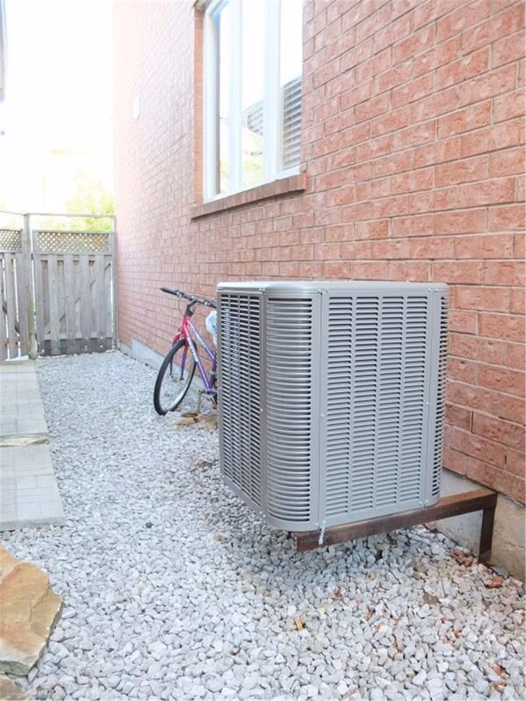 Professional outdoor air conditioner condenser installation by Reno Compass in Toronto. This energy-efficient HVAC unit is securely mounted on a raised stand with proper drainage and ventilation clearance, ensuring optimal cooling performance, durability, and safe operation for residential homes. Installed by licensed technicians for long-term reliability and comfort.