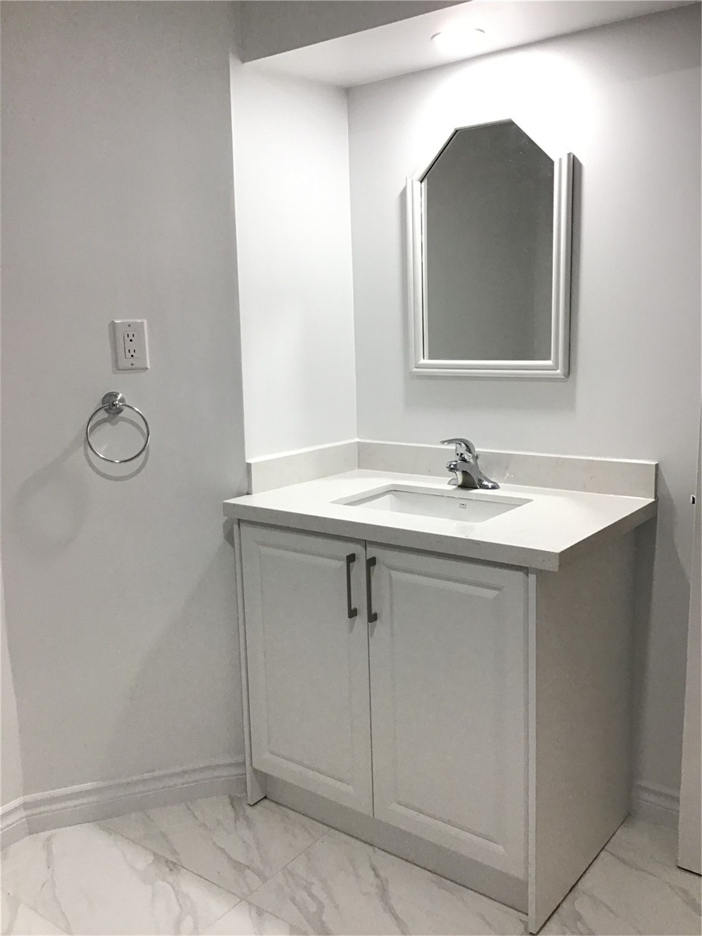This Whitby basement renovation includes a sleek and modern bathroom vanity installation with a white cabinet, quartz-style countertop, and contemporary mirror design. The marble-look floor tiles add elegance while maintaining durability and easy maintenance. Clean lines, neutral tones, and professional plumbing installation create a bright and functional basement bathroom space that enhances both comfort and home value.