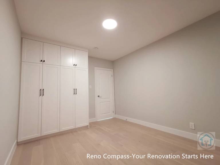 This bedroom renovation in Newmarket features custom-built white wardrobes with full-height storage, clean modern lines, and integrated hardware. Light-toned hardwood flooring, neutral wall colors, and recessed ceiling lighting create a bright and functional living space. Designed and completed by a Toronto renovation company, this project focuses on maximizing storage while maintaining a clean, minimal aesthetic suitable for everyday living.