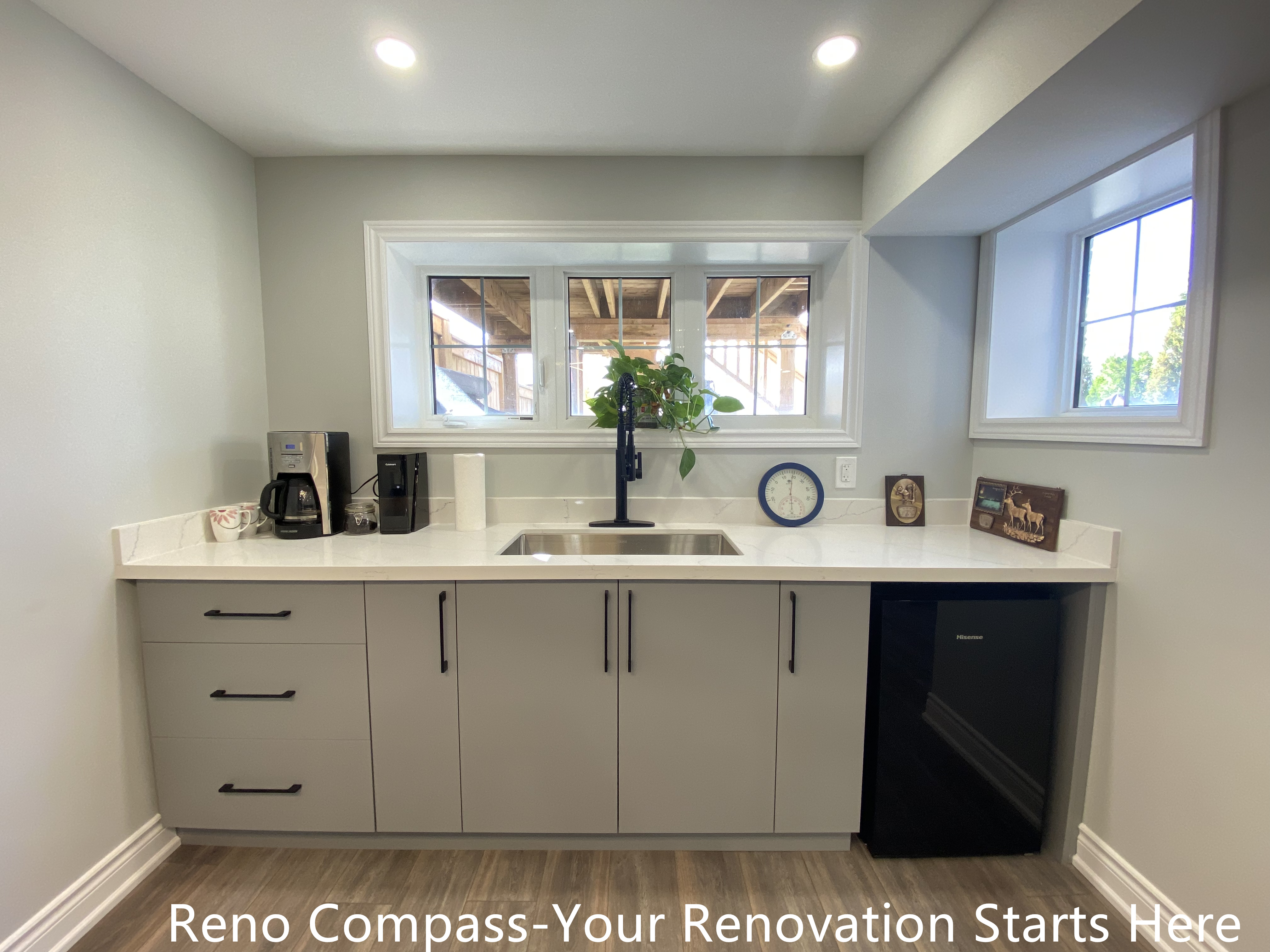 Basement wet bar renovation in Oakville featuring custom flat-panel cabinetry, quartz countertop, undermount sink, matte black faucet, built-in mini fridge, and recessed lighting, creating a clean and functional bar area for basement entertaining, completed by Reno Compass Inc.