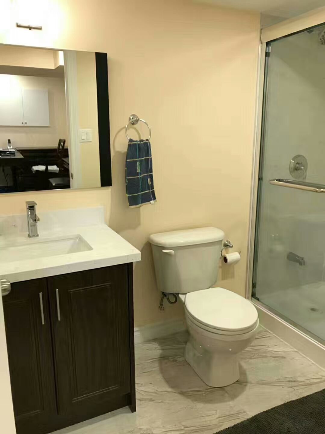 A clean and modern basement bathroom in a Vaughan renovation, featuring a glass‑enclosed shower, sleek vanity with dark cabinetry, updated fixtures, soft neutral walls, and marble‑style flooring. A functional and stylish addition to the finished basement.