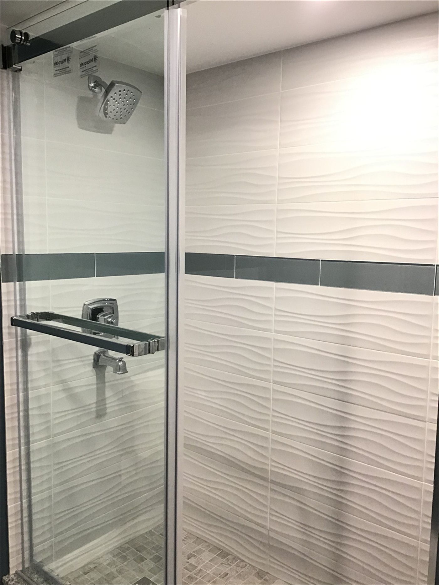 This Richmond Hill basement bathroom features a modern walk-in shower with a clear glass enclosure, sleek chrome fixtures, and textured wall tiles with a horizontal accent strip. The clean design enhances both functionality and visual appeal, making it ideal for contemporary basement renovations. A perfect example of stylish and durable shower installation in Richmond Hill.