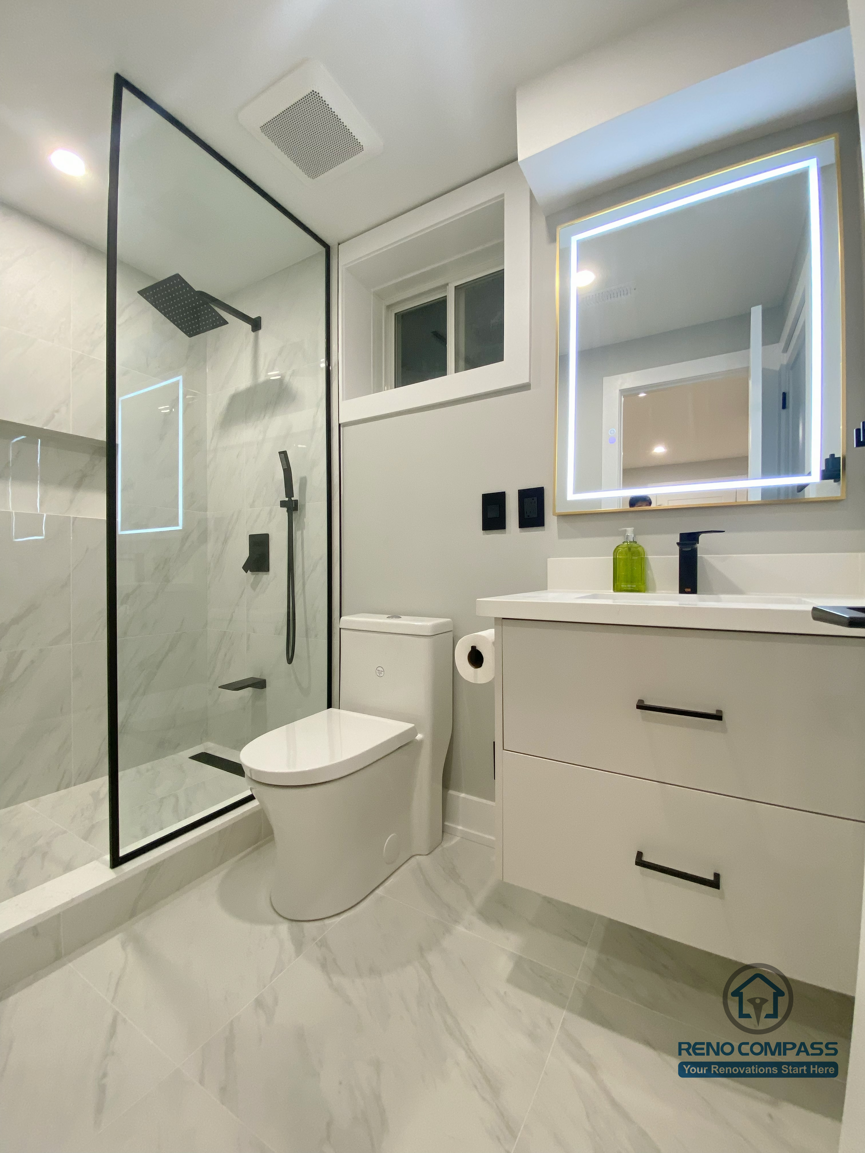 This Aurora basement renovation features a modern full bathroom with a glass-enclosed shower, marble-look wall and floor tiles, a floating vanity, and an LED-lit mirror. The compact layout is designed for efficiency and comfort, combining clean lines with durable finishes suitable for basement use. Completed by a Toronto renovation company, this basement bathroom renovation reflects thoughtful space planning and contemporary bathroom design standards.