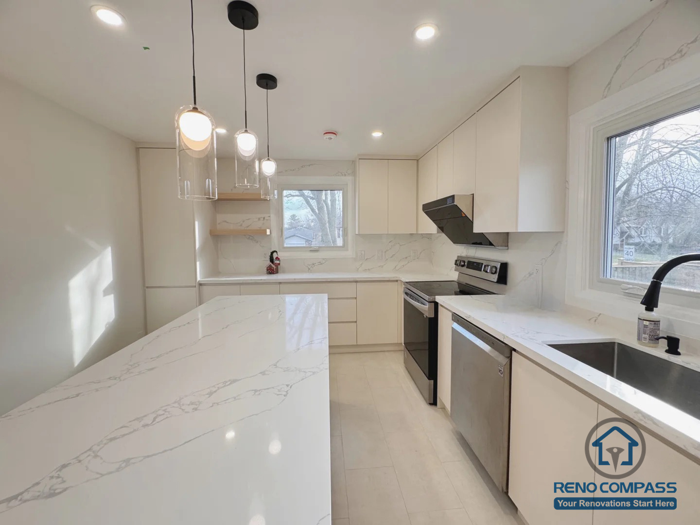 This Oakville kitchen renovation features a spacious quartz waterfall island, custom flat-panel cabinetry, and clean-lined pendant lighting. The layout was redesigned to improve workflow, storage efficiency, and natural light, creating a bright, functional space that supports both everyday cooking and family gatherings.