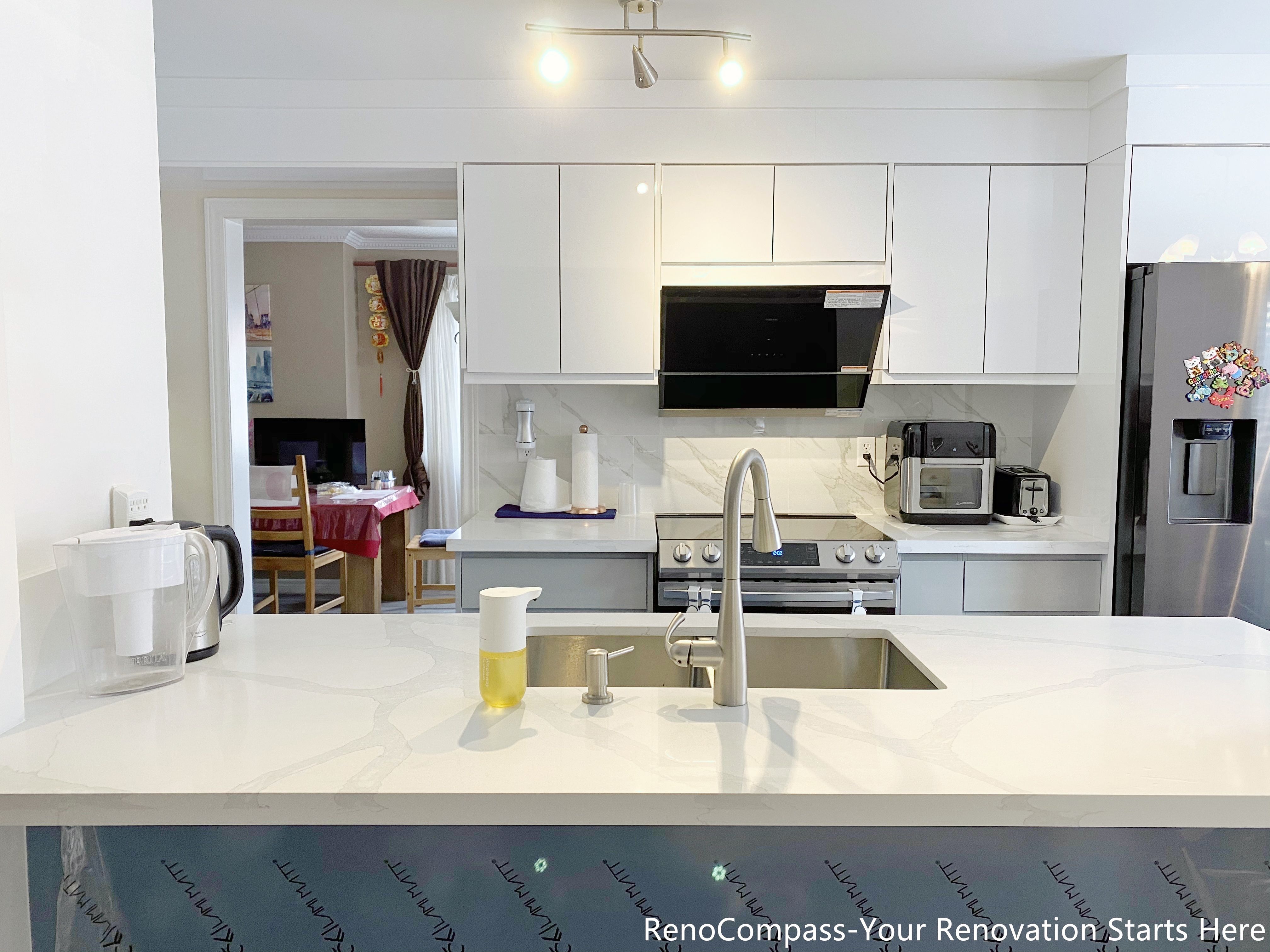 This image presents a modern kitchen renovation in Mississauga featuring full-height white cabinetry, integrated upper storage, and a clean appliance wall layout. The kitchen includes a stainless steel range, built-in hood, quartz countertops, and energy-efficient appliances, creating a balanced mix of functionality and visual clarity. Consistent cabinetry lines and neutral finishes improve workflow and storage efficiency, while the open layout supports everyday cooking and family use. This design reflects a practical and timeless approach to Mississauga kitchen renovations.