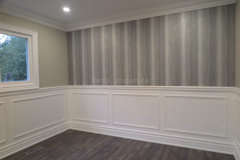 This Markham interior renovation project features elegant wall panel molding, modern grey accent wallpaper, and newly installed dark wood flooring. The space is enhanced with clean trim details, recessed lighting, and a refined contemporary design that elevates the overall home aesthetic. Completed by professional renovation contractor Reno Compass, delivering high-quality interior finishing and detailed craftsmanship in Markham and the Greater Toronto Area.