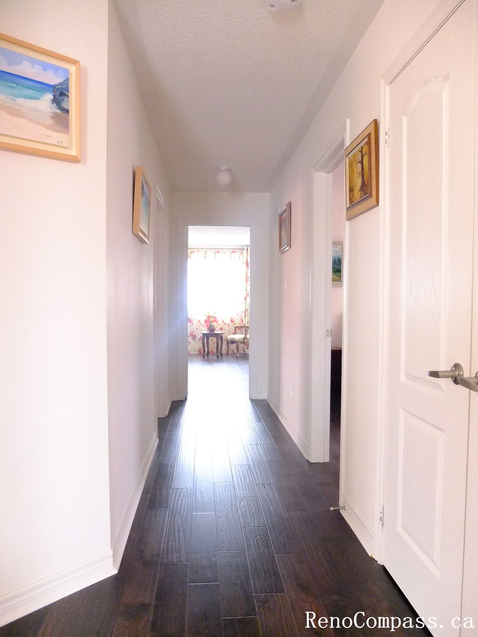 Toronto home hardwood flooring installation featuring deep-toned wood floors throughout the hallway and upper level. This professional flooring renovation enhances brightness, durability, and visual continuity, completed by Reno Compass for a clean and modern interior upgrade.