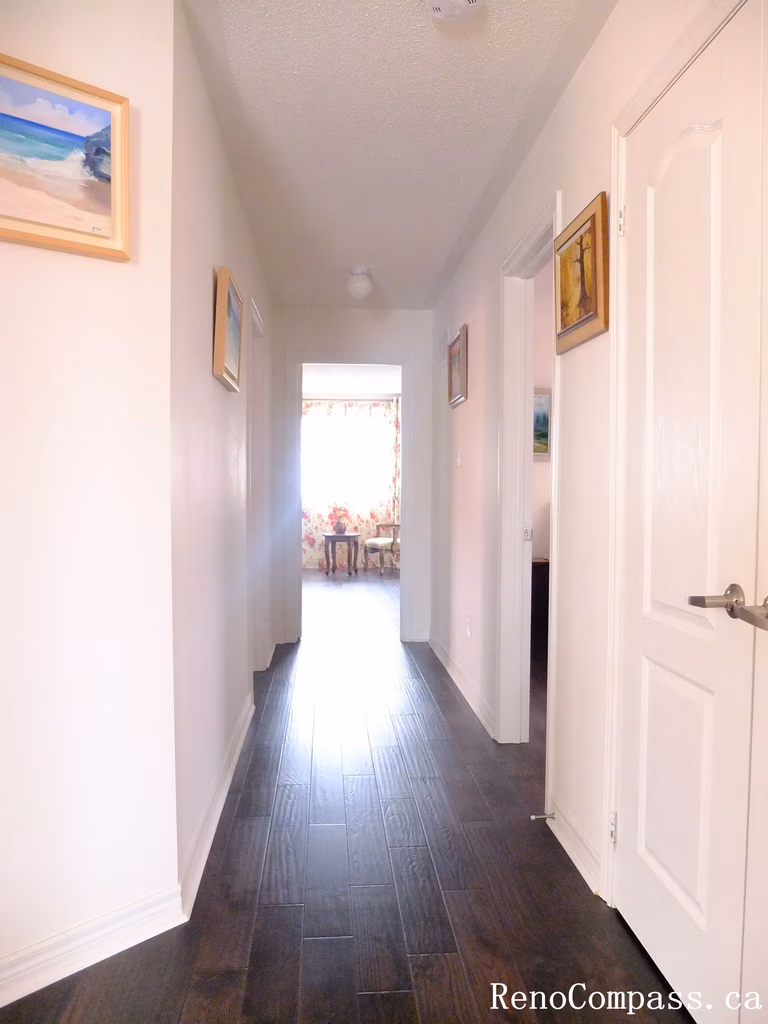 Toronto home hardwood flooring installation featuring deep-toned wood floors throughout the hallway and upper level. This professional flooring renovation enhances brightness, durability, and visual continuity, completed by Reno Compass for a clean and modern interior upgrade.