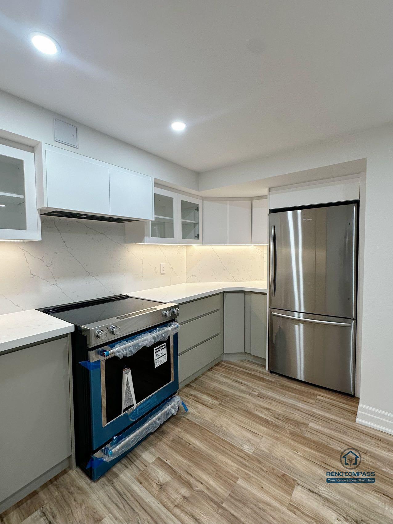 This image showcases a side-angle view of a completed basement kitchen renovation in Pickering, highlighting the integration of appliances within a clean and efficient layout. Custom cabinetry, built-in appliances, and continuous countertop surfaces support smooth workflow and everyday usability. Under-cabinet lighting enhances visibility across the workspace, while neutral finishes and consistent flooring help the kitchen blend seamlessly into the surrounding basement living area. The overall design prioritizes functionality, durability, and long-term use within a multi-purpose lower-level environment.
Location: Pickering · Toronto Contractor: Reno Compass