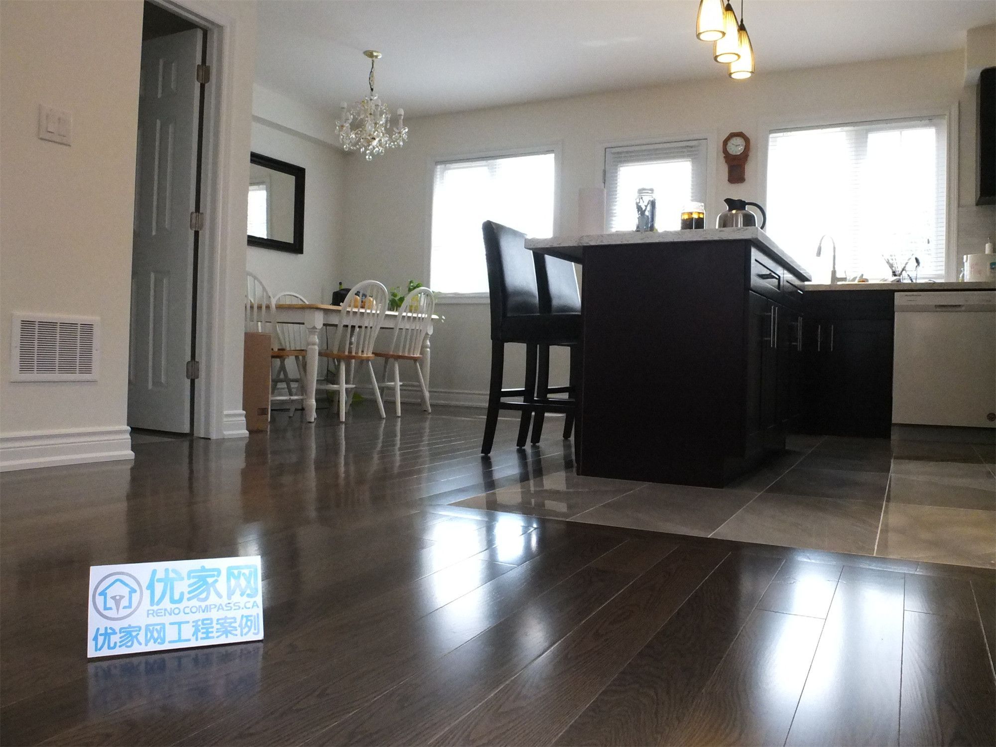 Open-concept kitchen and dining space from a Scarborough home addition project featuring dark hardwood flooring, a central kitchen island, pendant lighting, and a bright dining area. The renovation improves layout flow and creates a modern, functional living space for everyday family use.