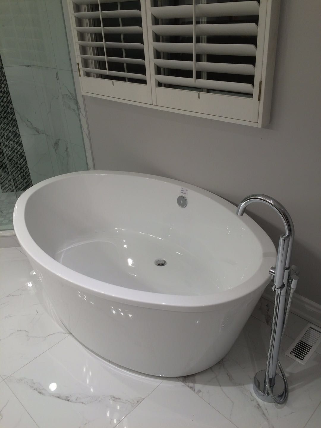 This Toronto bathroom renovation features a modern freestanding bathtub paired with a sleek floor-mounted faucet, creating a clean and luxurious spa-like atmosphere. Marble-style floor tiles and minimalist finishes enhance the sense of space and elegance. The upgraded bathtub area improves both comfort and visual appeal, offering a refined and relaxing bathing experience in a contemporary home.