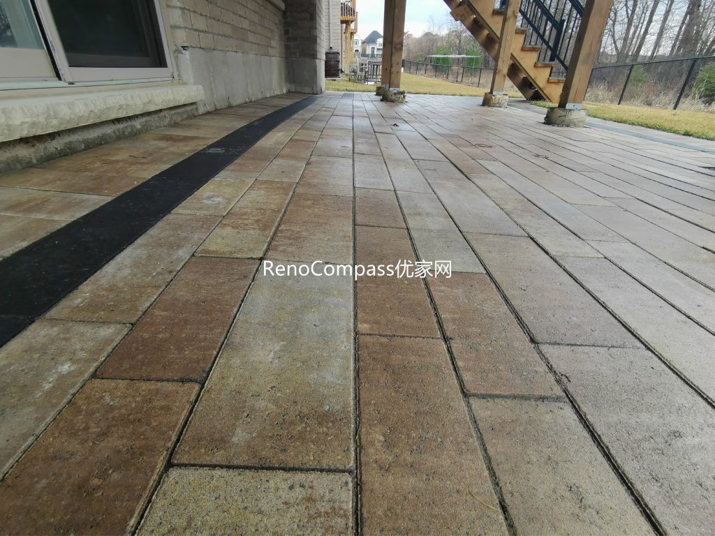 Professional interlocking patio installation in Aurora featuring durable stone pavers and clean border detailing beneath an elevated deck. This custom outdoor renovation improves drainage, usability, and backyard aesthetics while creating a functional covered patio space for all-season outdoor living.