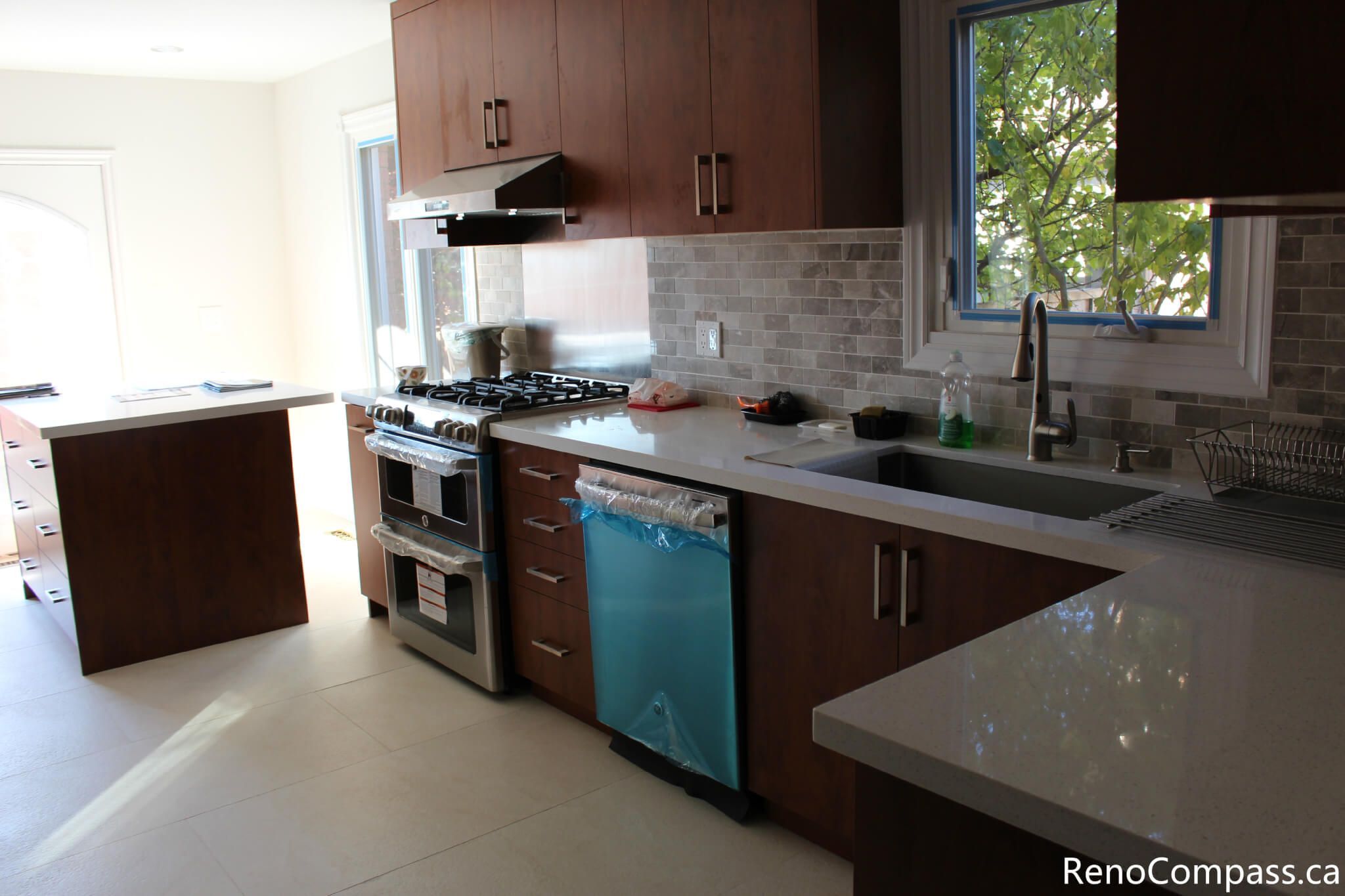 This modern kitchen is part of a full house renovation project in Mississauga completed by a professional Toronto renovation team. The space features rich wood cabinetry, quartz countertops, a contemporary backsplash, and stainless steel appliances, creating a warm yet modern cooking environment. The renovation focused on improving functionality, storage efficiency, and overall home value while delivering a clean and timeless kitchen design suitable for everyday family living.