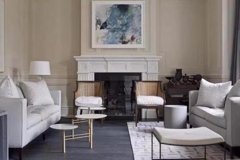 This Toronto interior design project presents a refined living room that blends classic architectural detailing with modern furnishings. The traditional fireplace mantel serves as a focal point, complemented by soft neutral upholstery, layered textures, and tailored drapery. Natural light enhances the subtle color palette, while carefully selected accent tables and seating create balance and visual harmony. Designed and completed by Reno Compass Inc., this space demonstrates how timeless elements can be seamlessly integrated into contemporary interior styling.