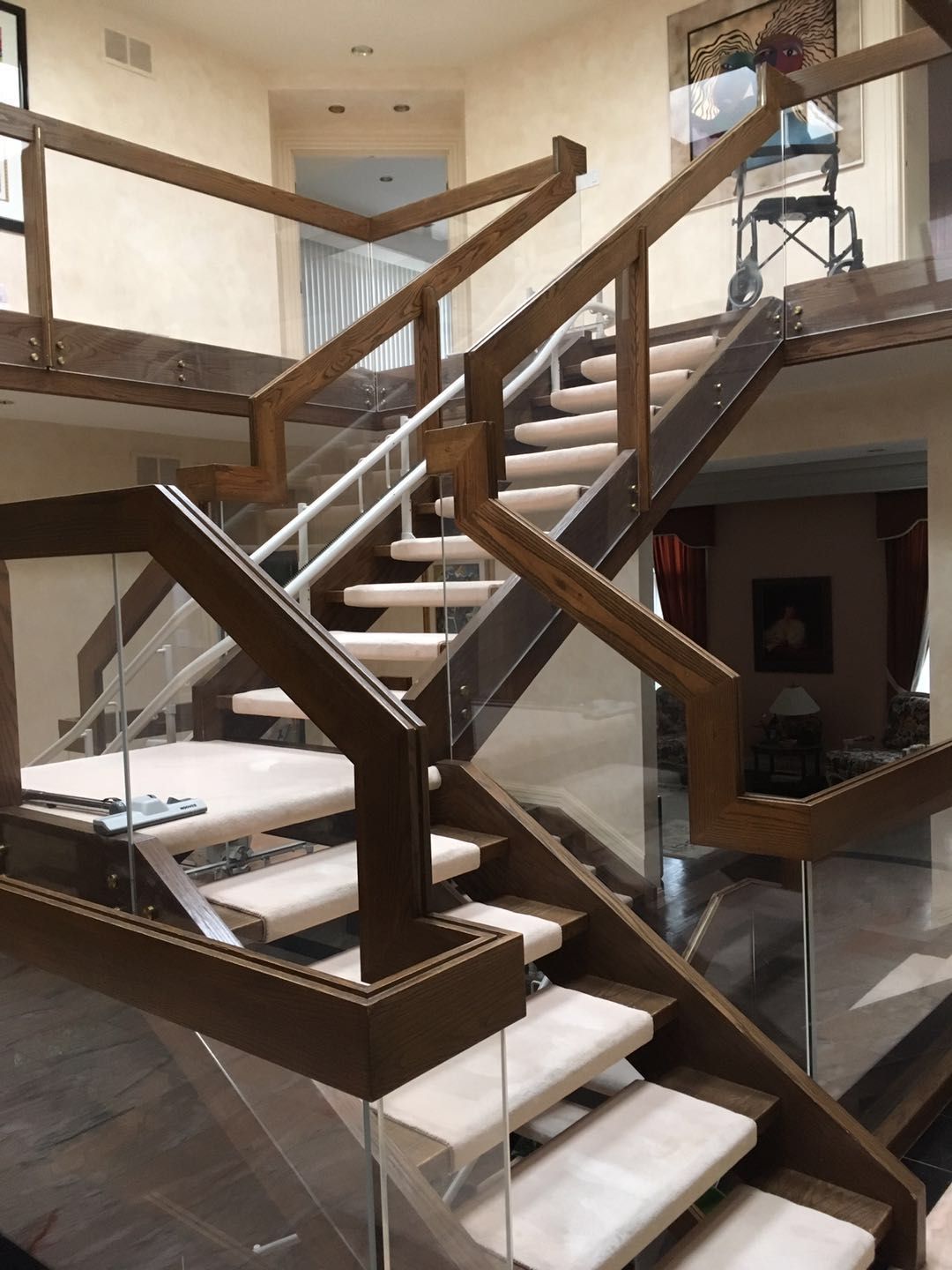 This Toronto interior renovation features a beautifully crafted custom staircase with rich wood framing, glass panel railings, and elegant light-toned stair treads. The multi-level open design enhances visual flow while maintaining safety and durability. Modern glass guardrails allow natural light to travel throughout the space, creating a bright and sophisticated interior atmosphere. Completed by a professional Toronto renovation company, this staircase renovation highlights detailed craftsmanship, structural precision, and contemporary residential design.