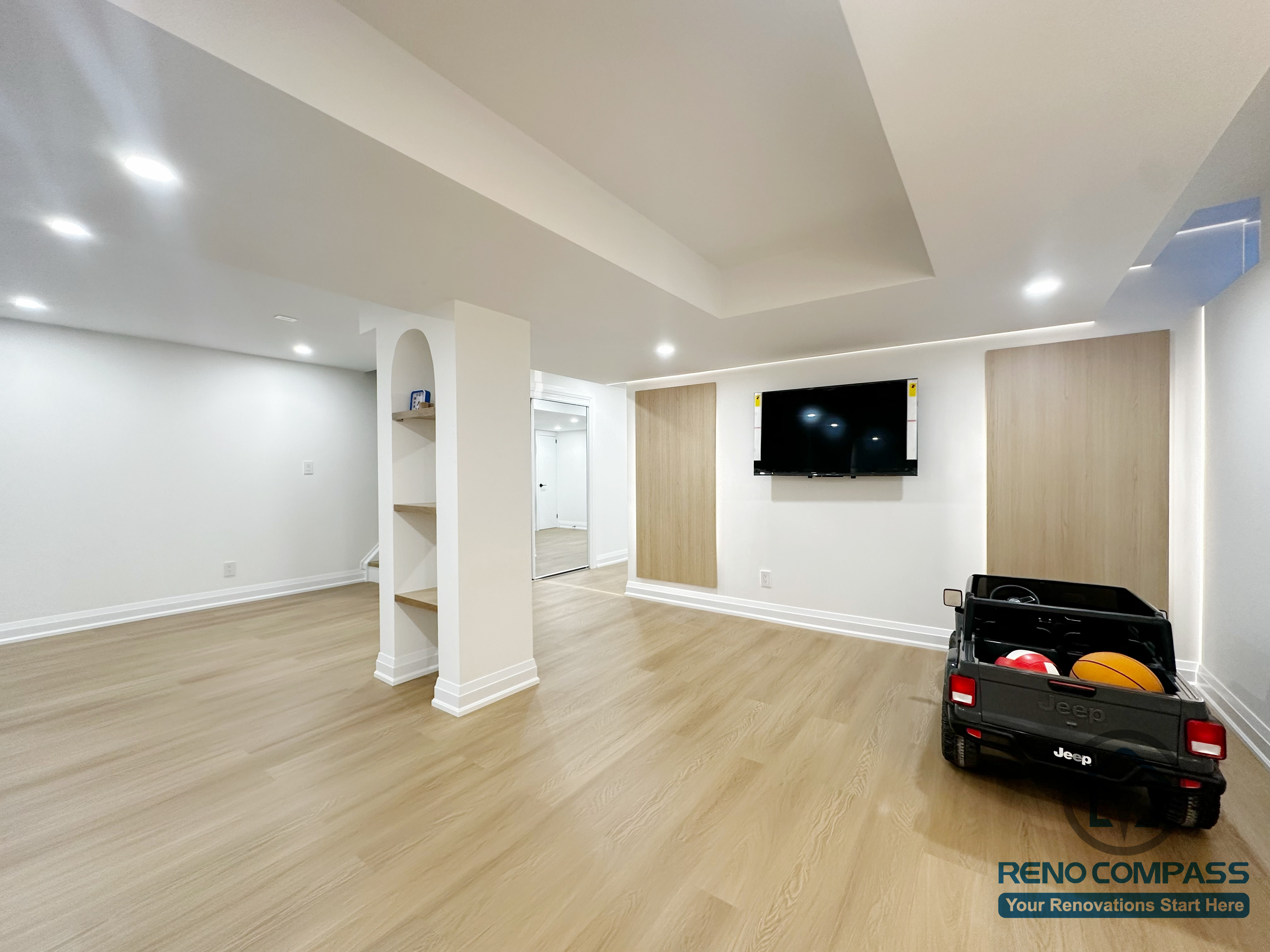 Spacious open-concept basement renovation in Markham featuring custom built-in shelving, recessed lighting, and light wood flooring. The layout supports recreation, play, and future multipurpose use while maintaining a clean, well-structured interior.