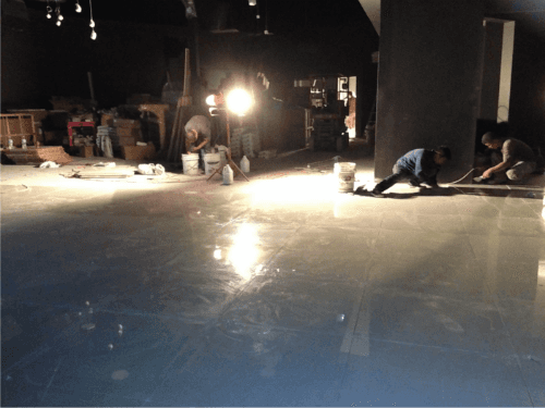 This image captures the flooring installation phase of a 7000 sqft private club renovation project in Toronto. Professional contractors are applying and finishing the commercial-grade flooring system, ensuring durability, smooth surface leveling, and long-term performance for a high-traffic entertainment venue.

The project involves careful surface preparation, material application, and lighting coordination to achieve a polished and reflective finish suitable for a luxury lounge and nightlife environment. Large-scale commercial renovations like this require precise workmanship and experienced project management to maintain quality standards.

Completed by an experienced Toronto renovation team, this private club transformation demonstrates expertise in commercial construction, structural preparation, and high-end interior finishing.

该图片展示多伦多7000尺私人俱乐部装修项目的地面施工阶段，施工团队正在进行商业级地坪铺设与表面处理，确保地面平整度、耐用性与后期使用效果。

该项目地面工程注重基础处理与材料施工质量，为高端娱乐会所营造光洁、耐磨且具反光效果的地面表现。由专业多伦多装修团队执行，体现大型商业空间装修的施工标准与技术实力。