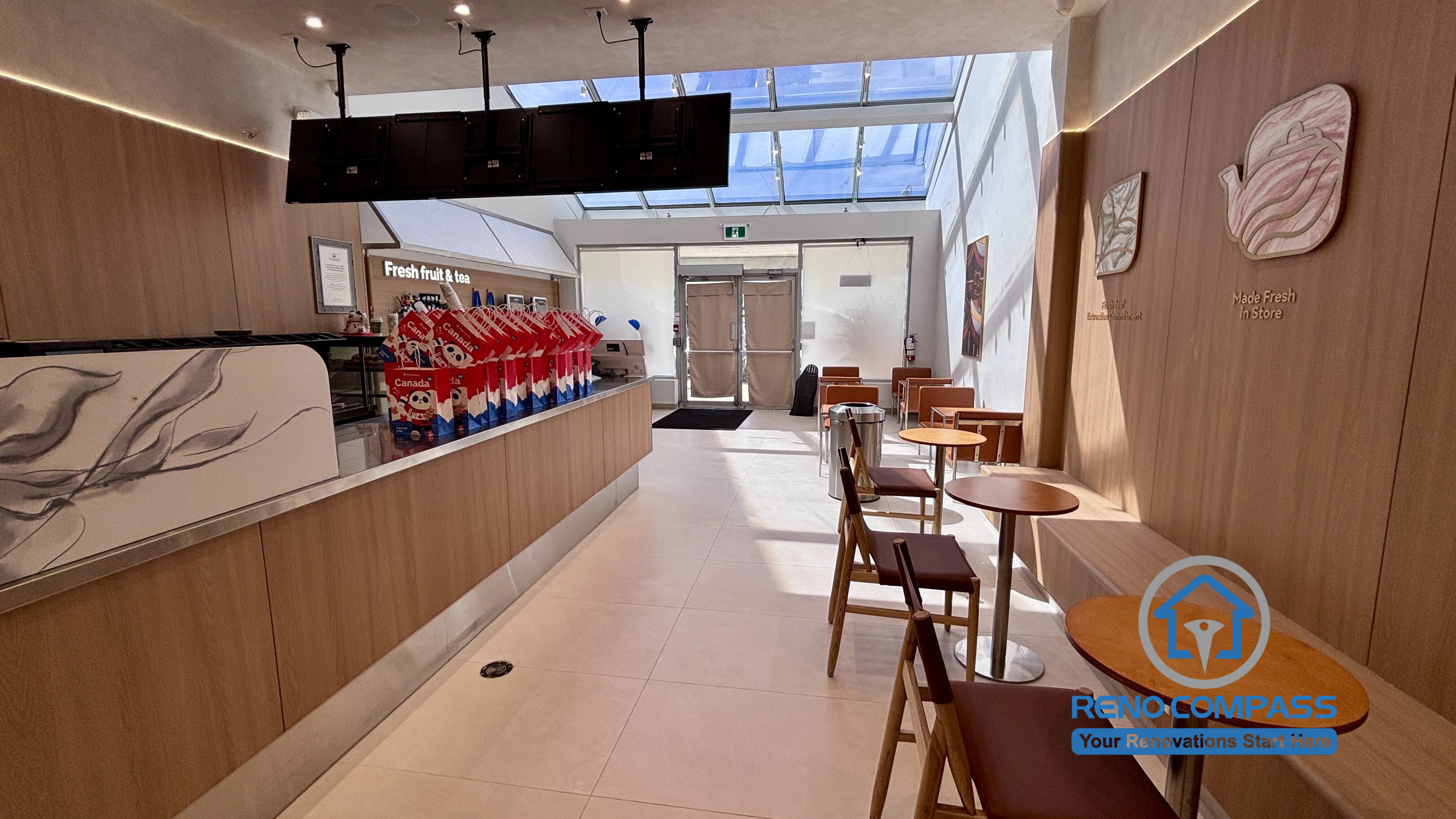Modern TEABYDO bubble tea shop renovation completed in Richmond Hill featuring custom wood-tone service counters, minimalist seating area, integrated LED lighting, skylight ceiling, and clean café-style commercial interior design. This Toronto GTA commercial renovation project was completed by Reno Compass with a focus on customer flow, functionality, and modern branding aesthetics.